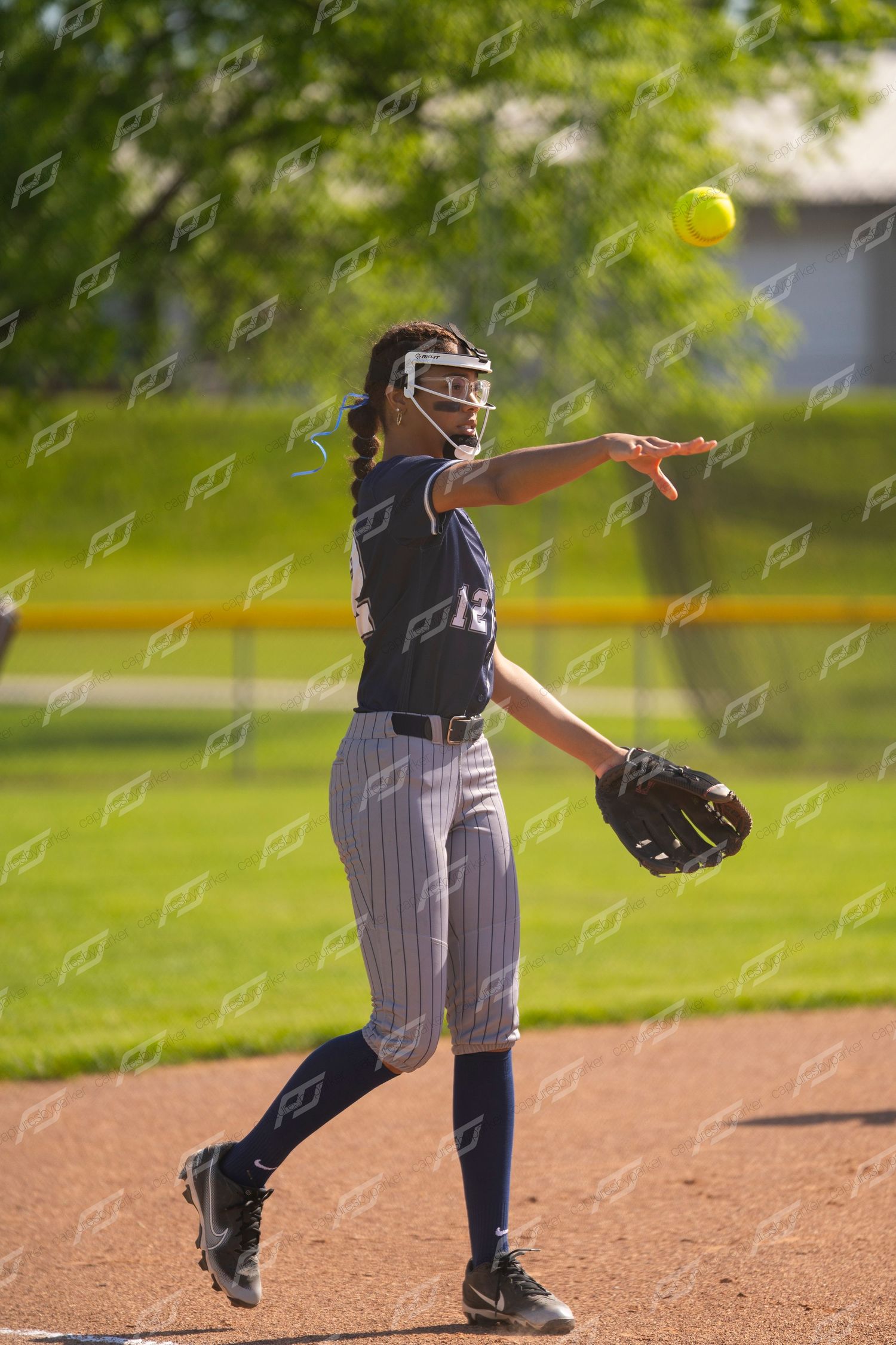 Female softball player throws the ball across the infield during a game.