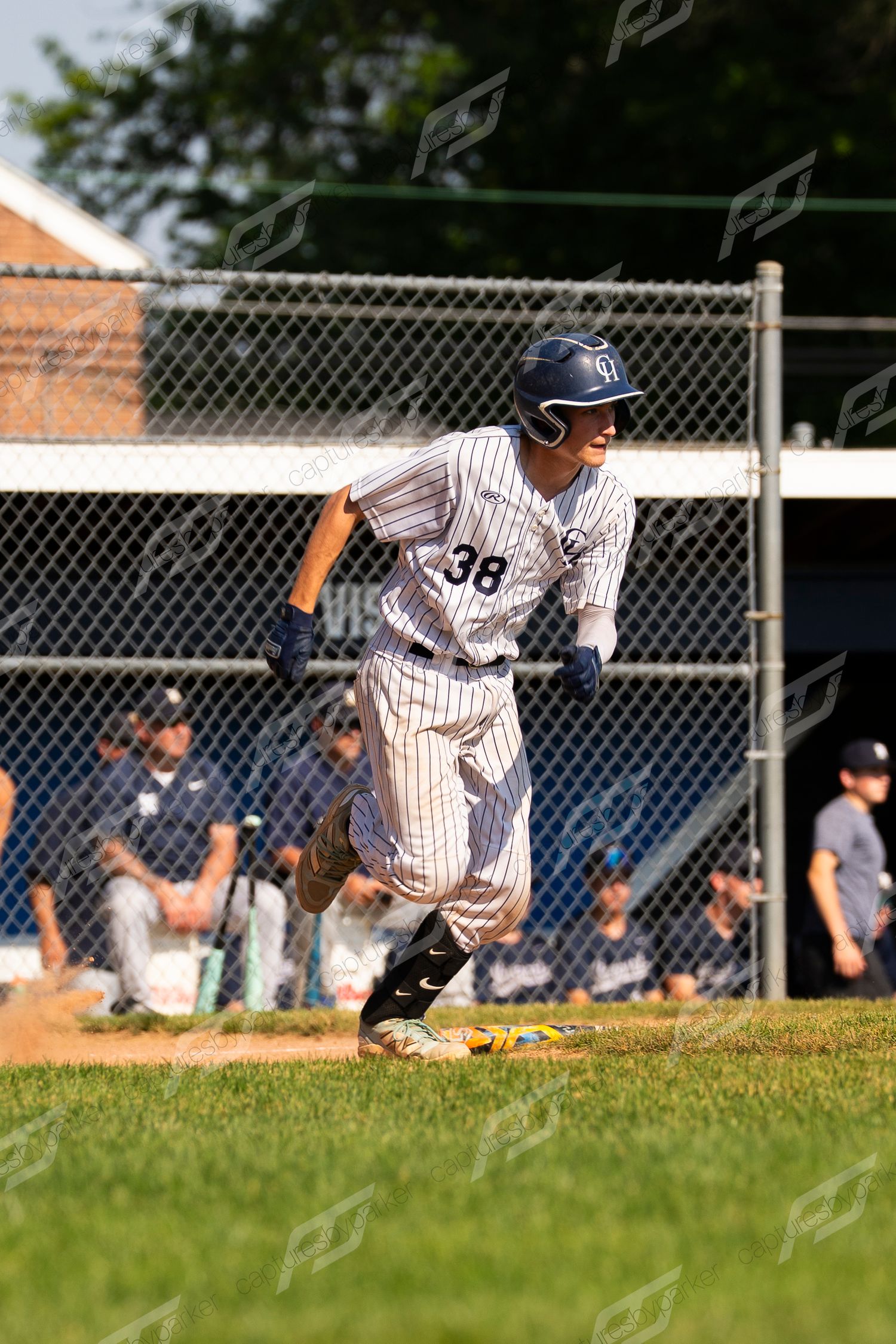 Youth baseball player #38 in pinstripe uniform running bases during a summer league game.
