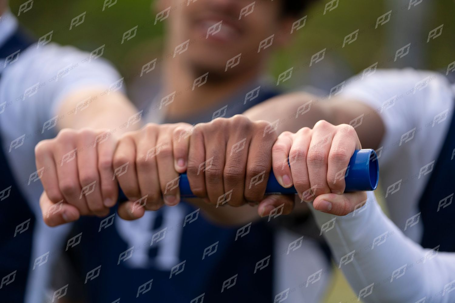 Close-up of athletes joining fists together in a team unity gesture outdoors.