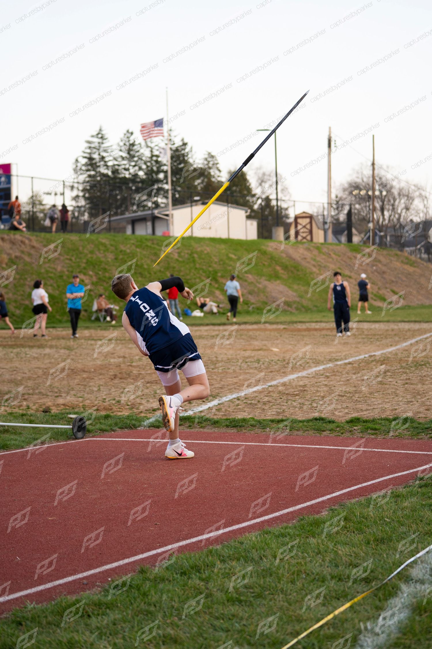 Male Lions athlete in follow-through stance after throwing javelin outdoors.