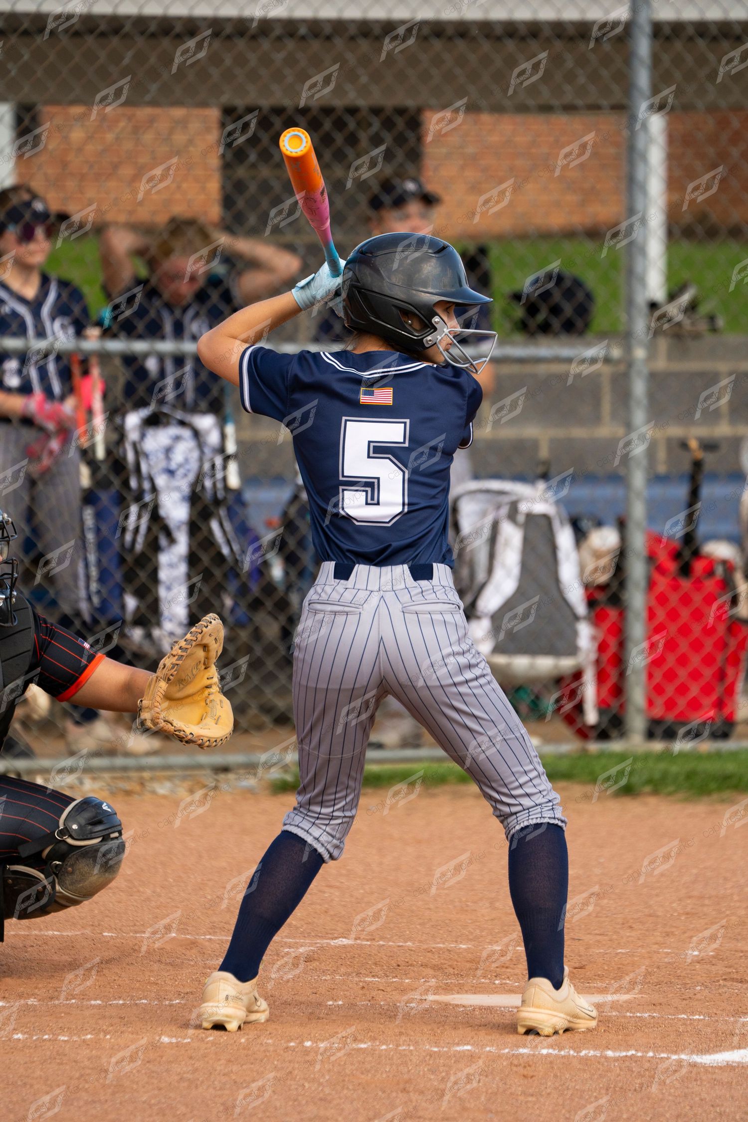 Female softball player number 5 in CH navy uniform stands ready to bat at home plate.