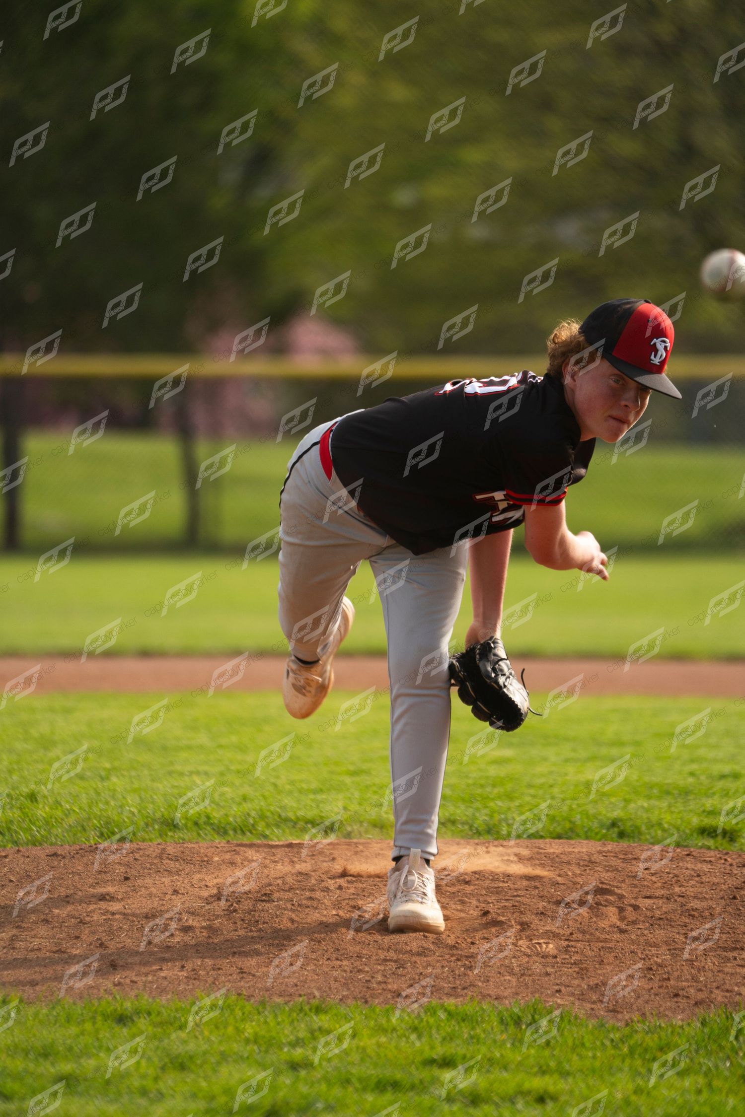 Hanna baseball pitcher in black uniform completing a full follow-through after delivering a pitch from the mound.