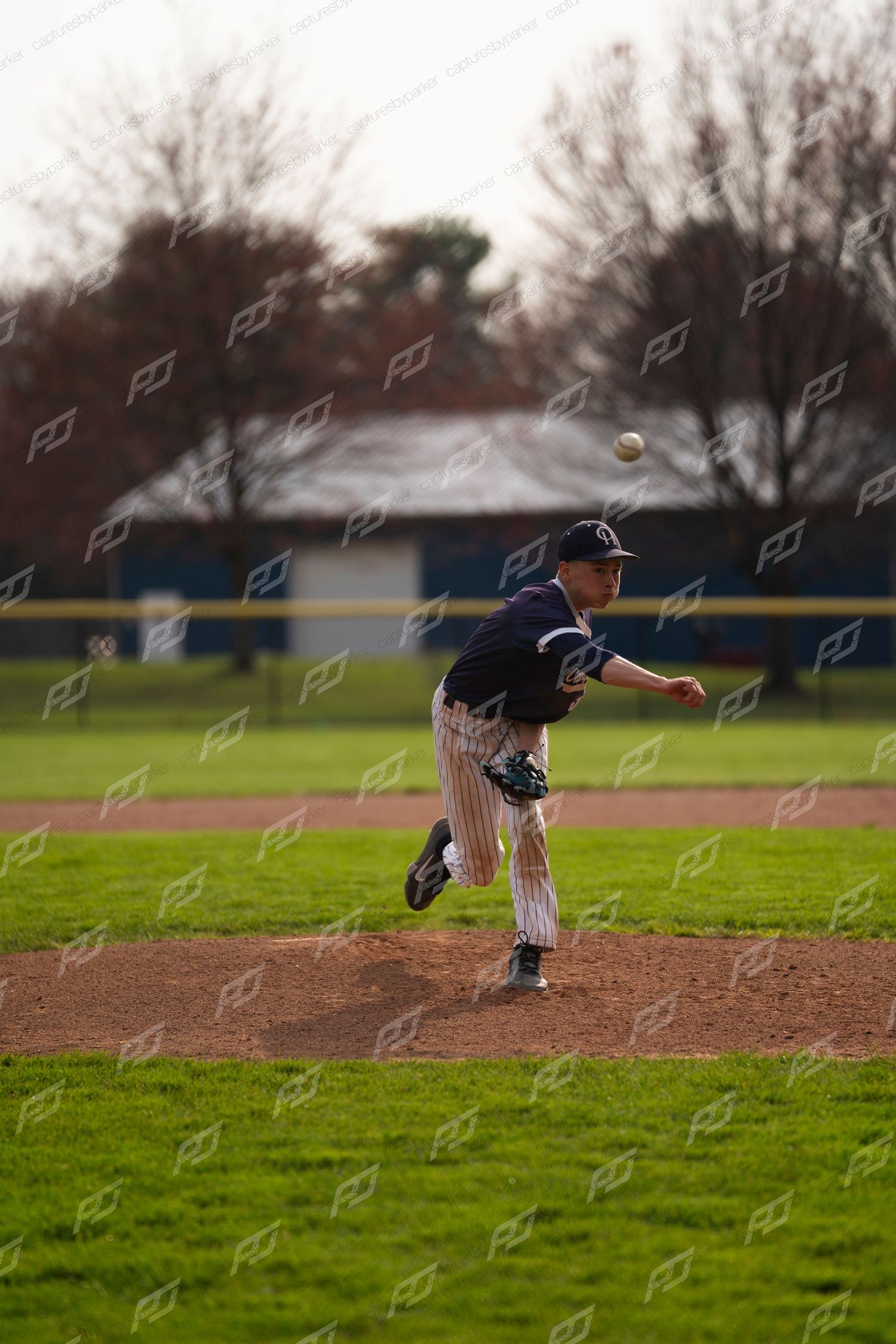 Baseball pitcher in navy pinstripe uniform releasing a pitch from the mound.