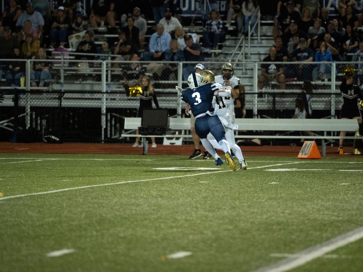 Camp Hill player number 3 makes a catch near the sideline during a nighttime high school football game.