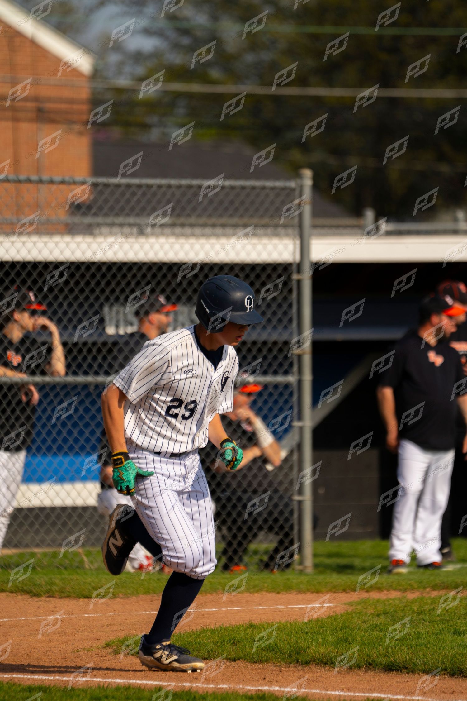 Baseball player #29 in white pinstripe uniform running bases during a youth baseball game.