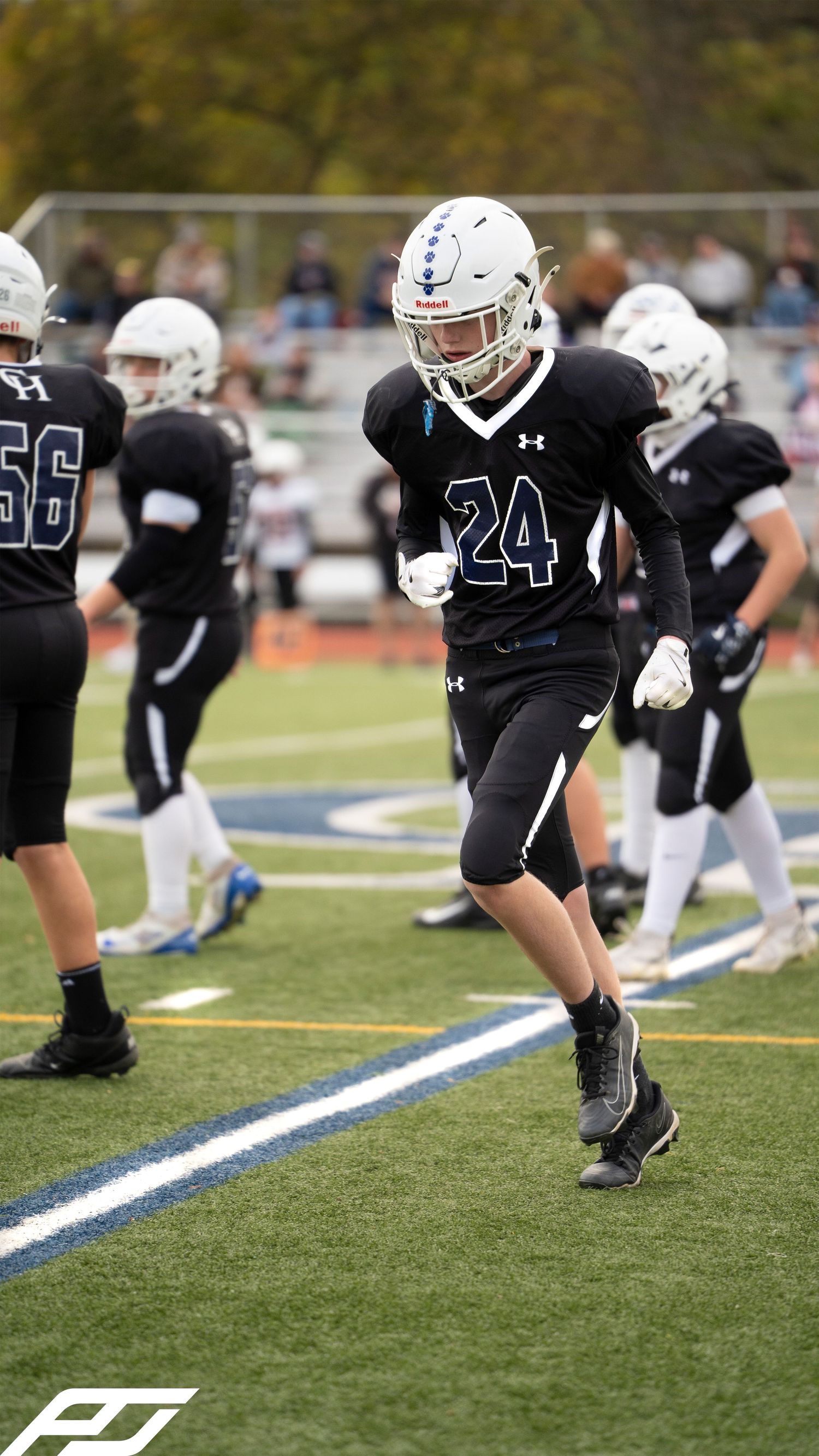 Youth football player #24 in black uniform sprints on green turf during a game.