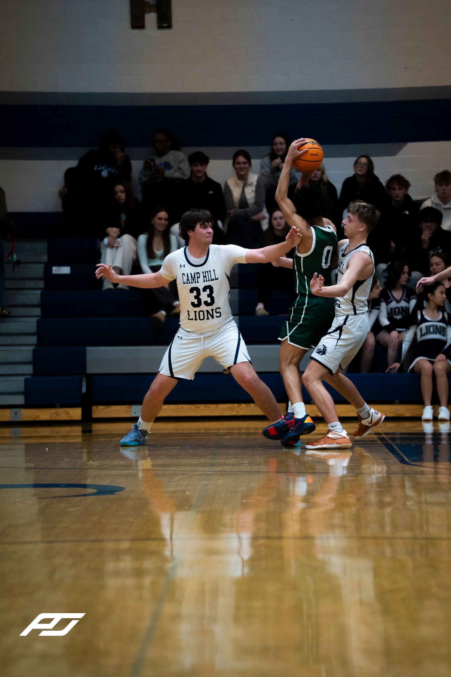 Camp Hill Lions #33 plays defense against opponent #0 during a high school basketball game.