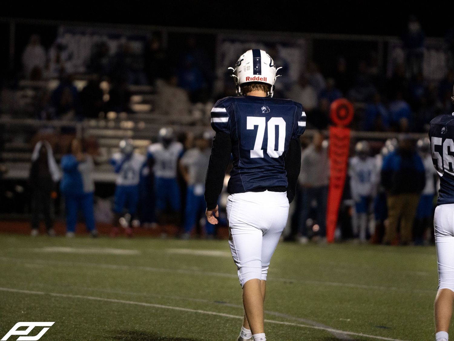 Camp Hill Lions football player number 70 walks across the field during a night game.