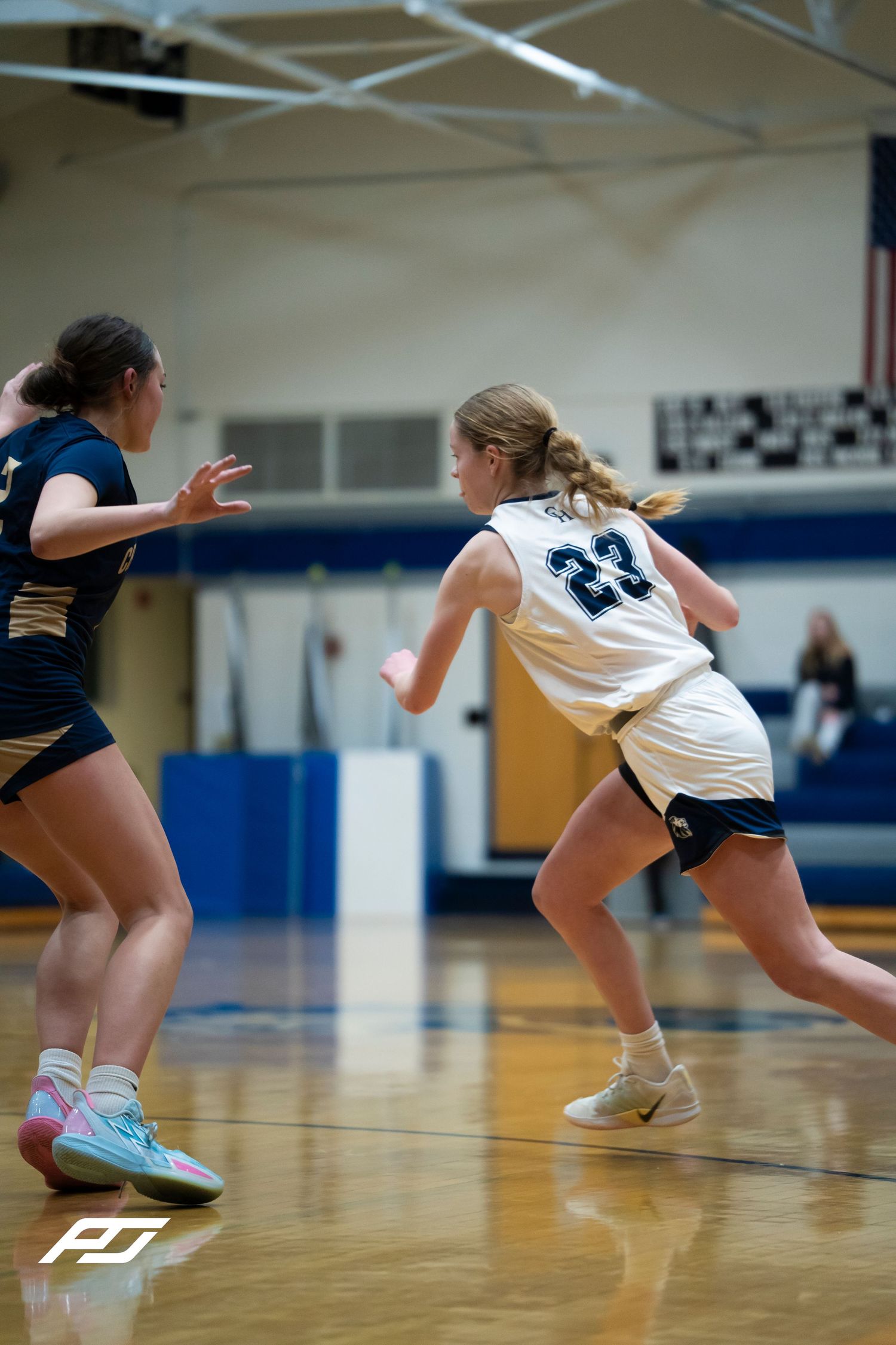 Lions #23 female basketball player sprints past a defender during a high school girls basketball game.