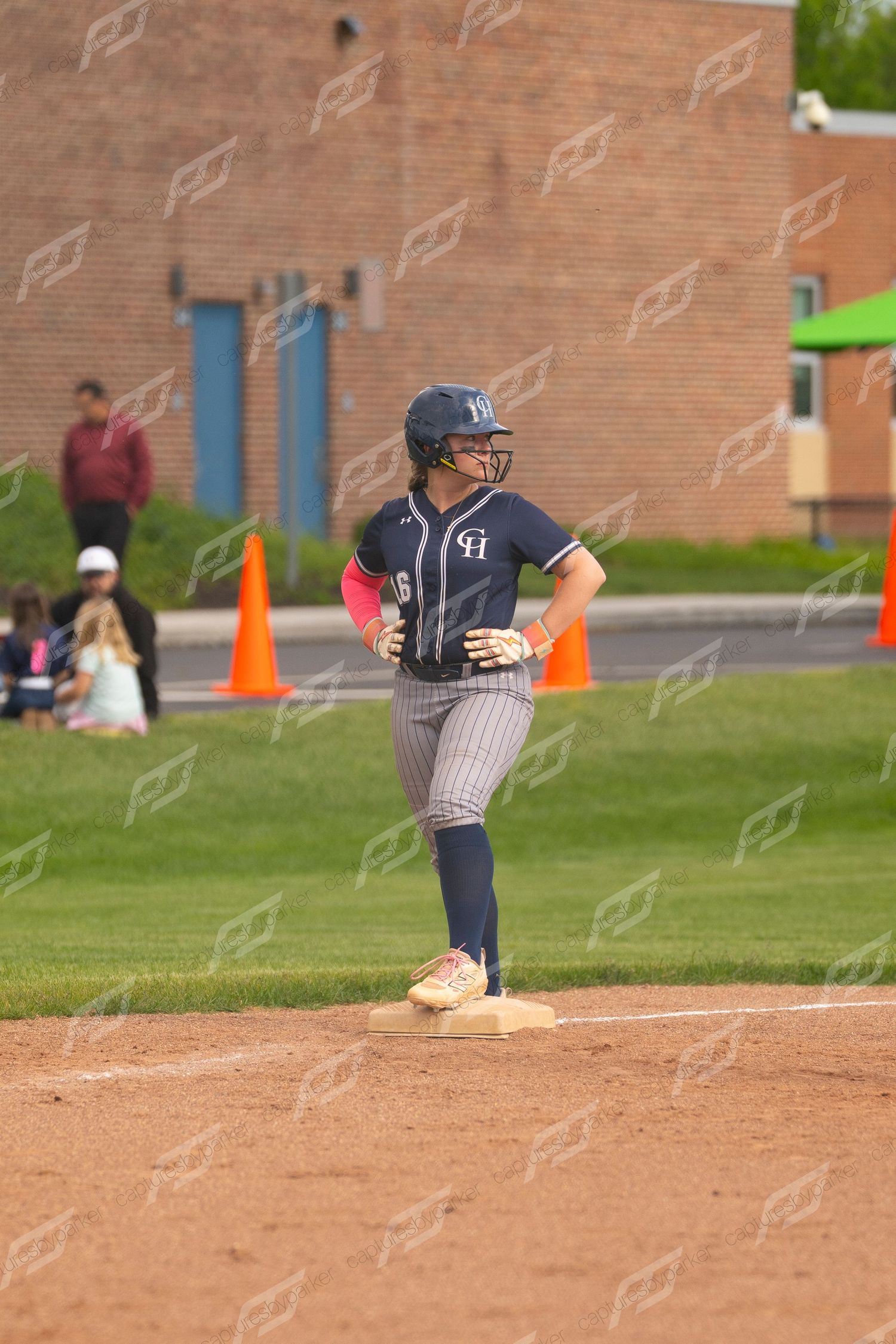 Softball player in navy pinstripe uniform stands on first base during a game.