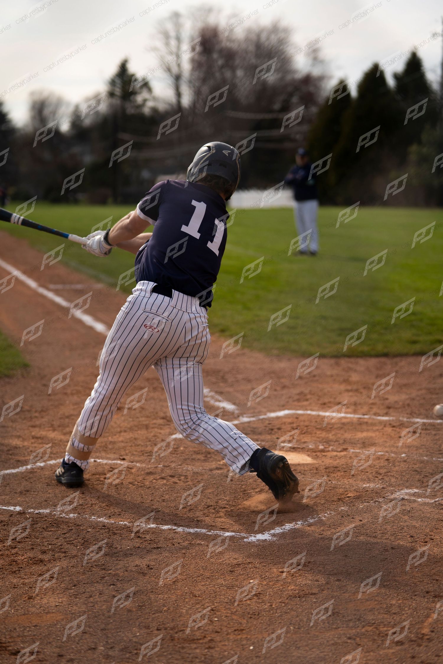 Baseball player #11 in navy uniform completes a full swing at home plate during a game.