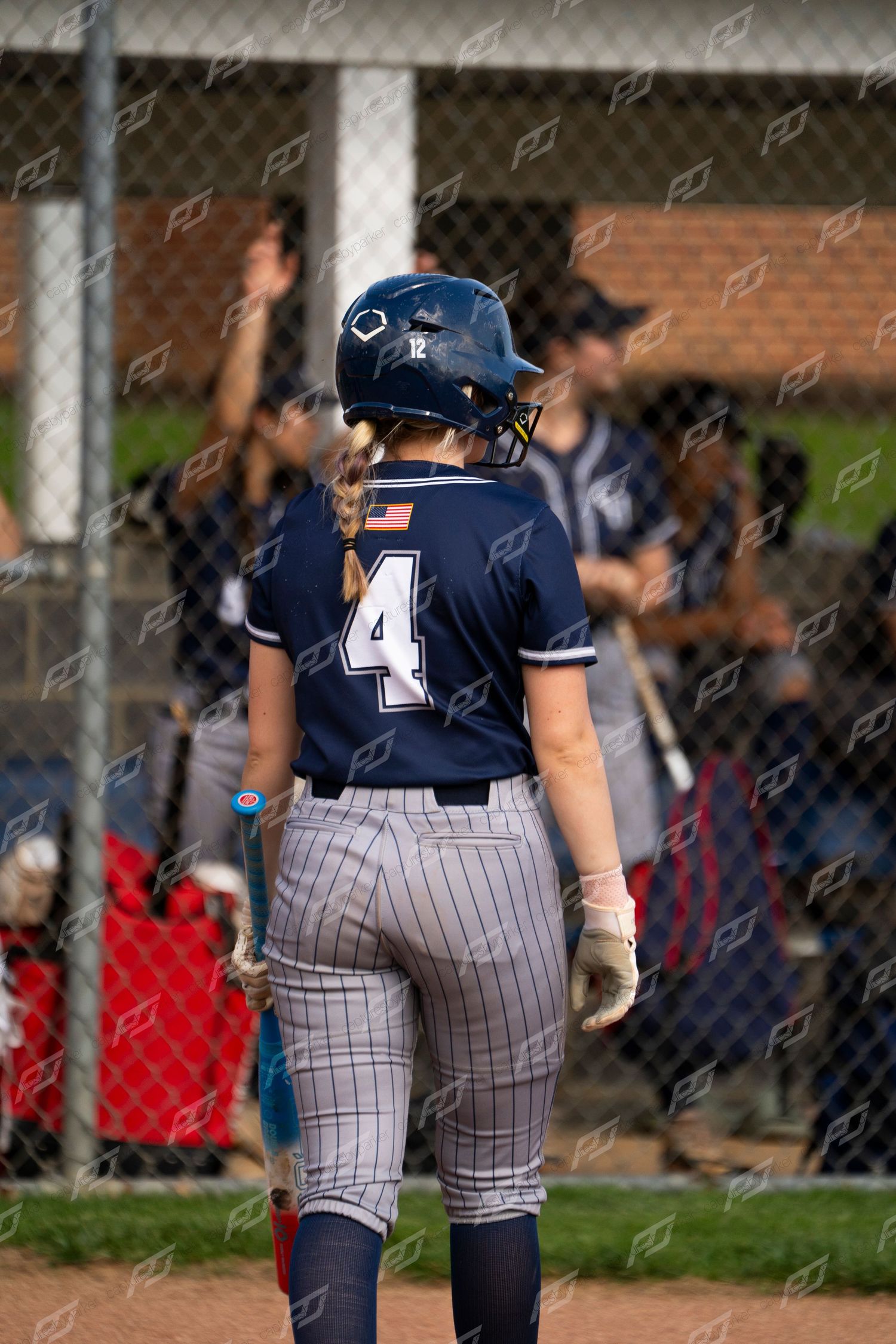 Softball player wearing number 4 in CH navy uniform stands near home plate.