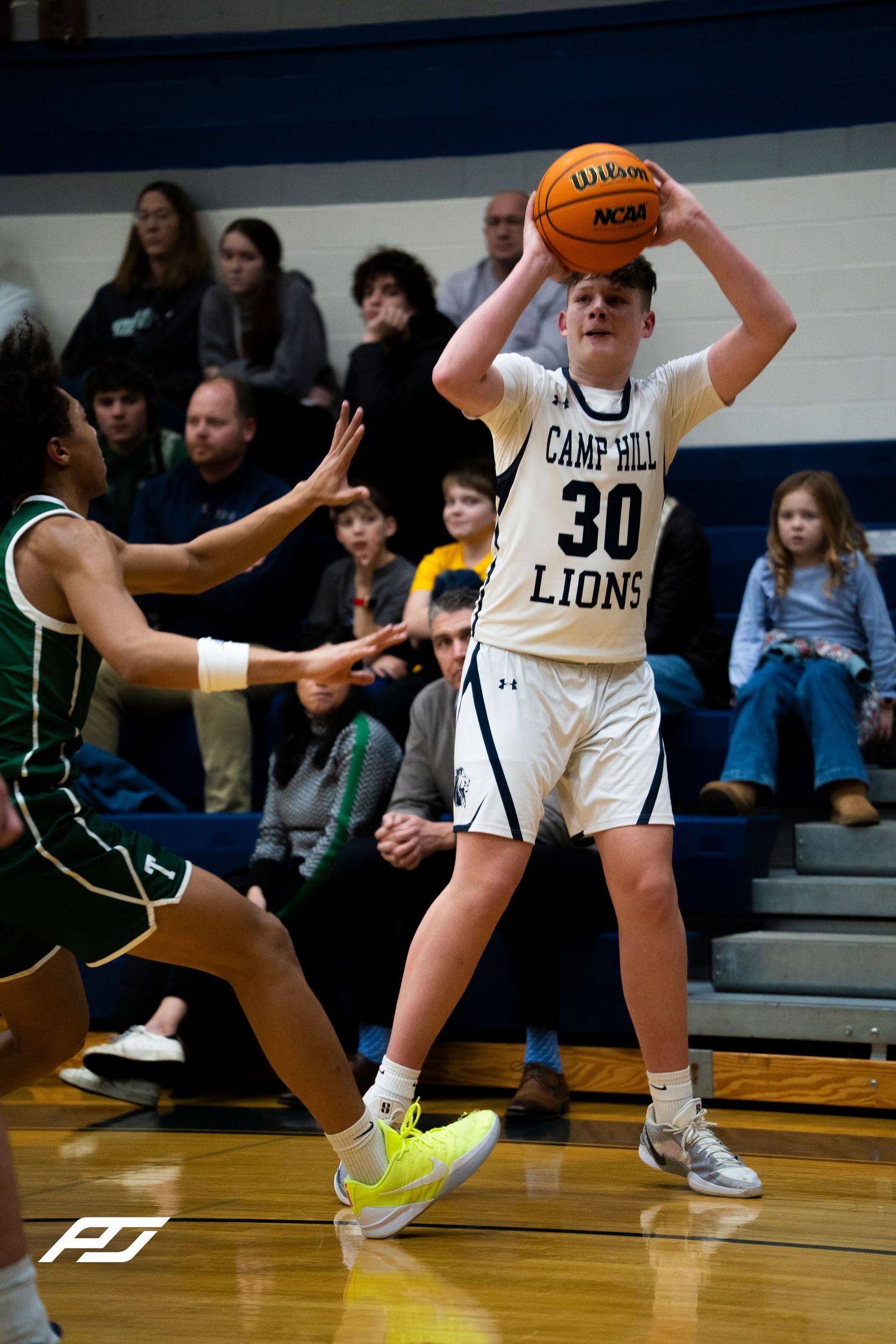 Camp Hill Lions #30 shoots over Trinity defender during home high school basketball game.