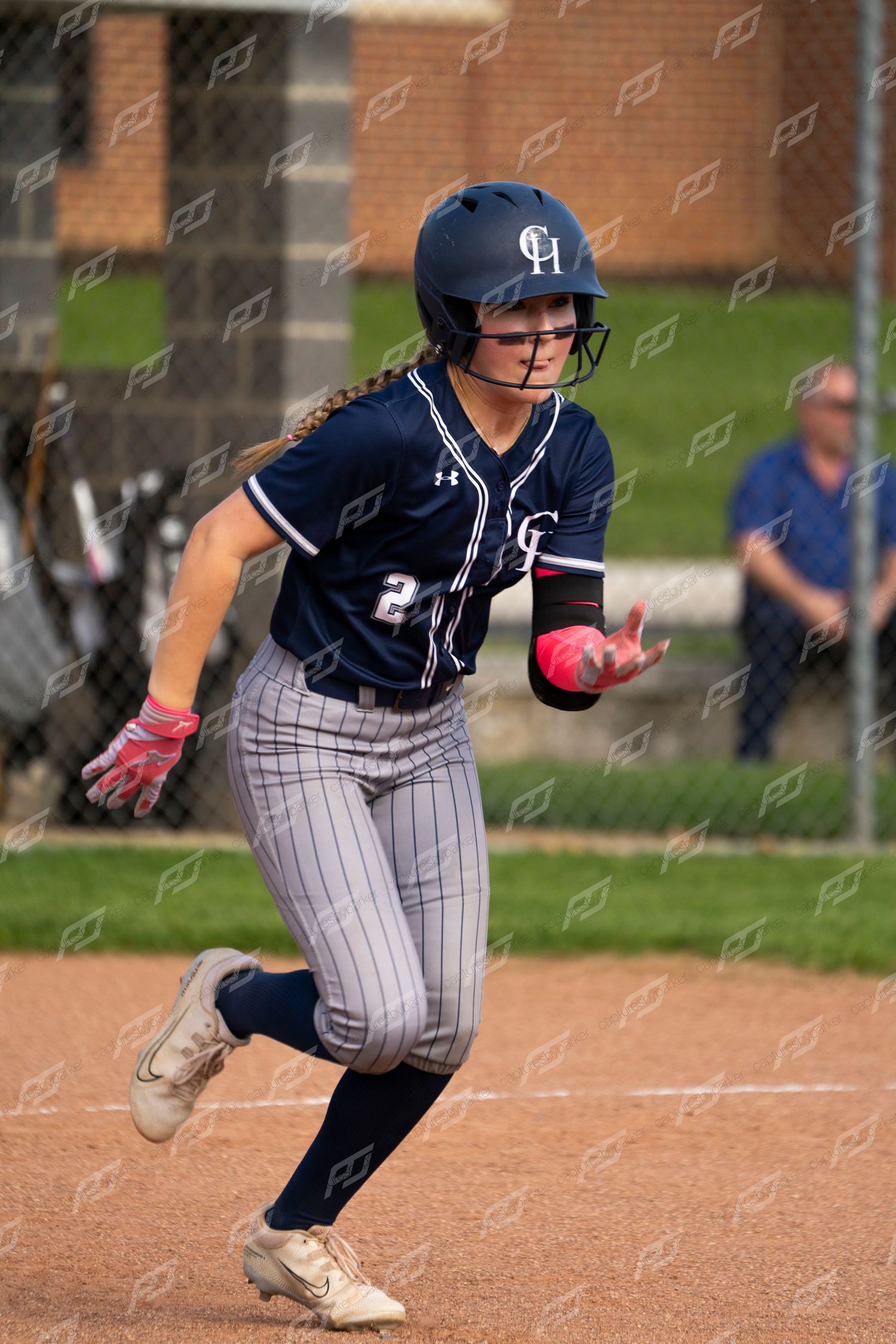 Female softball player number 2 sprints toward base during a game in navy uniform.