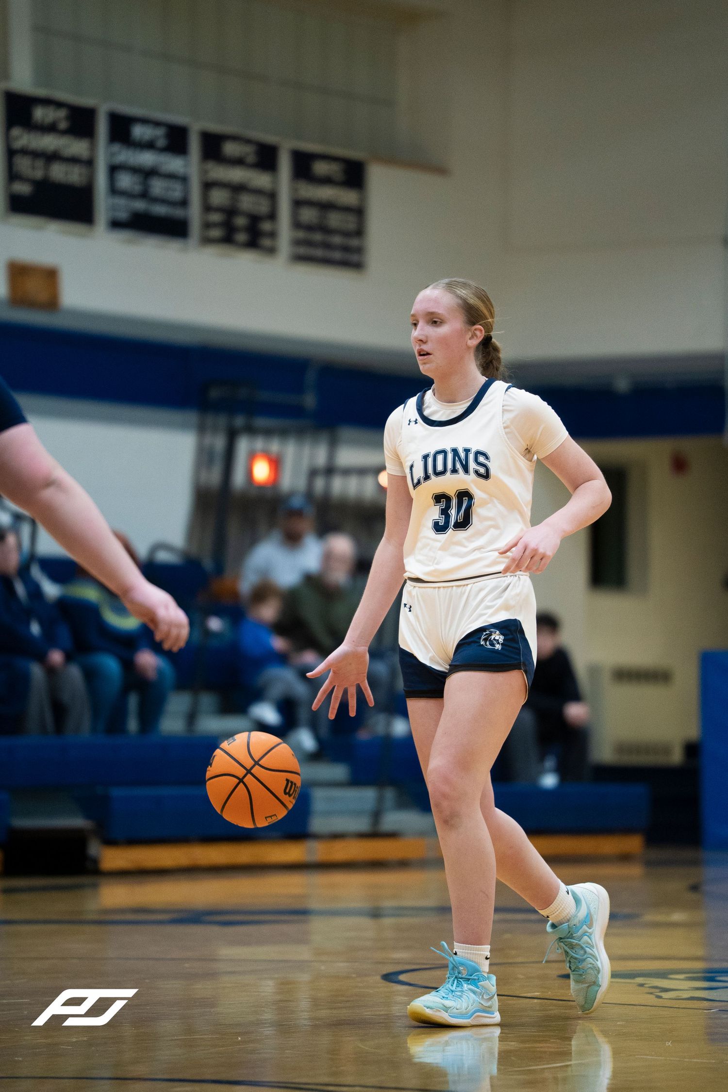 Lions #30 female basketball player dribbles the ball during a high school girls basketball game.