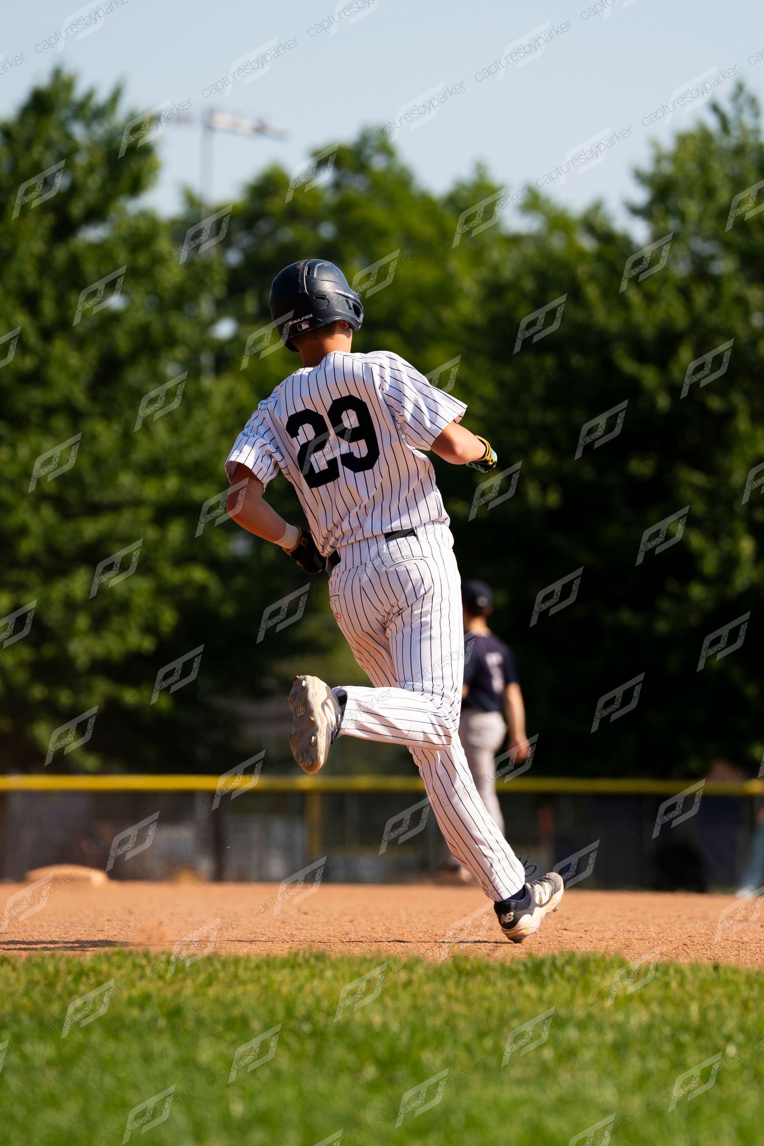 Baseball player #29 in white pinstripe uniform running the bases on a sunny afternoon game.