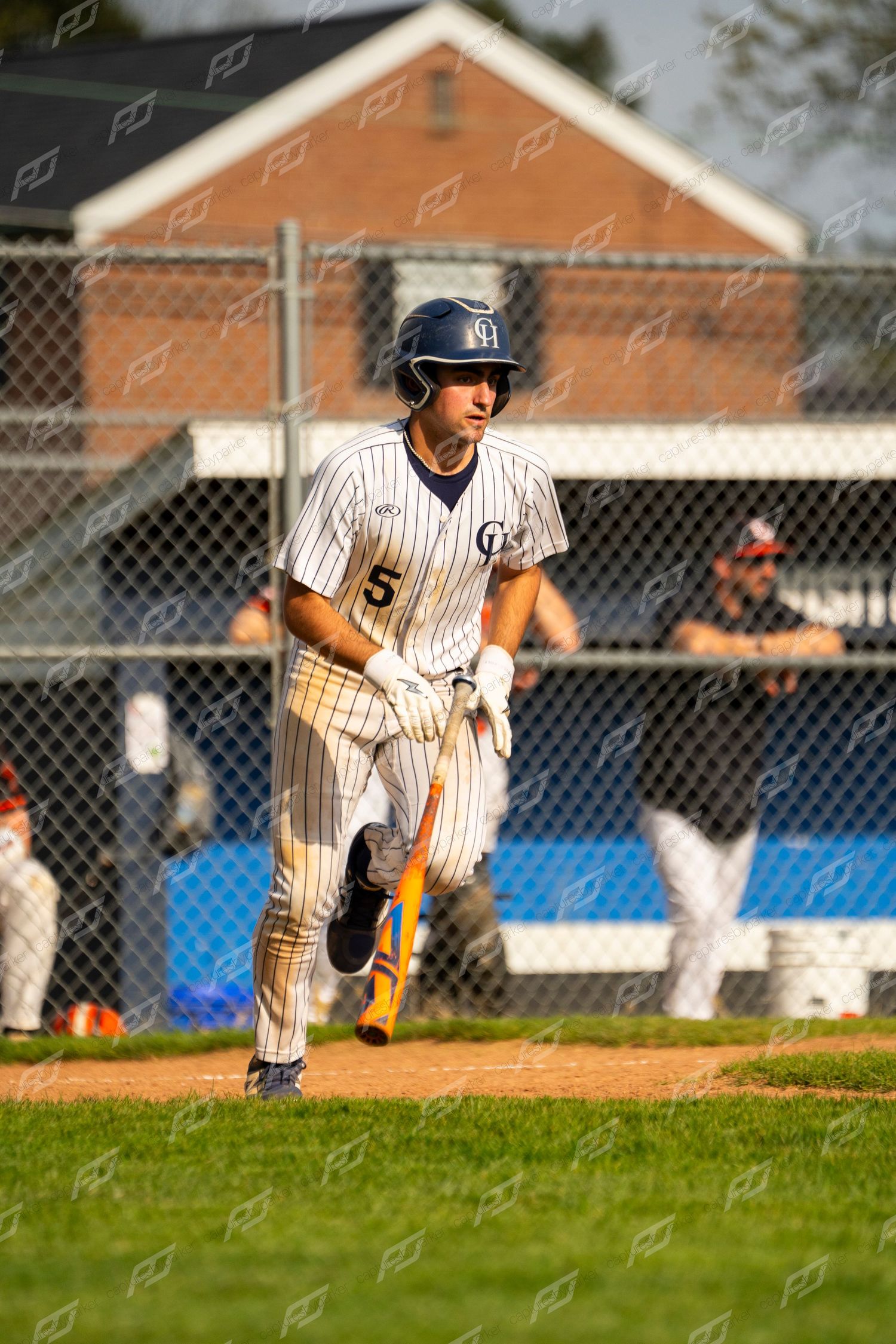 Baseball player number 5 in pinstripe uniform runs from home plate carrying a bat.