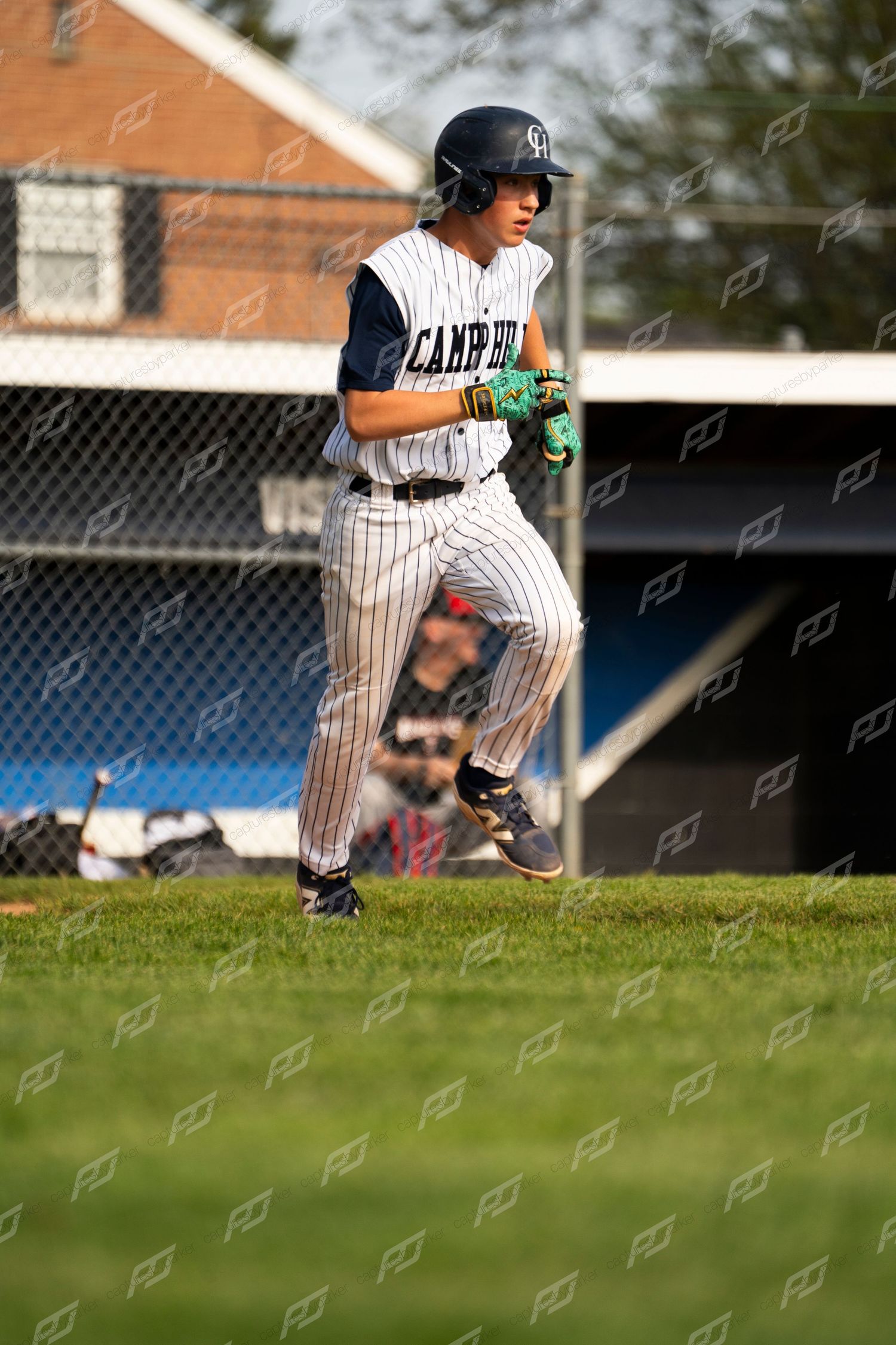 Camp Hill baseball player in pinstripe uniform running the bases wearing a black helmet and teal batting gloves.