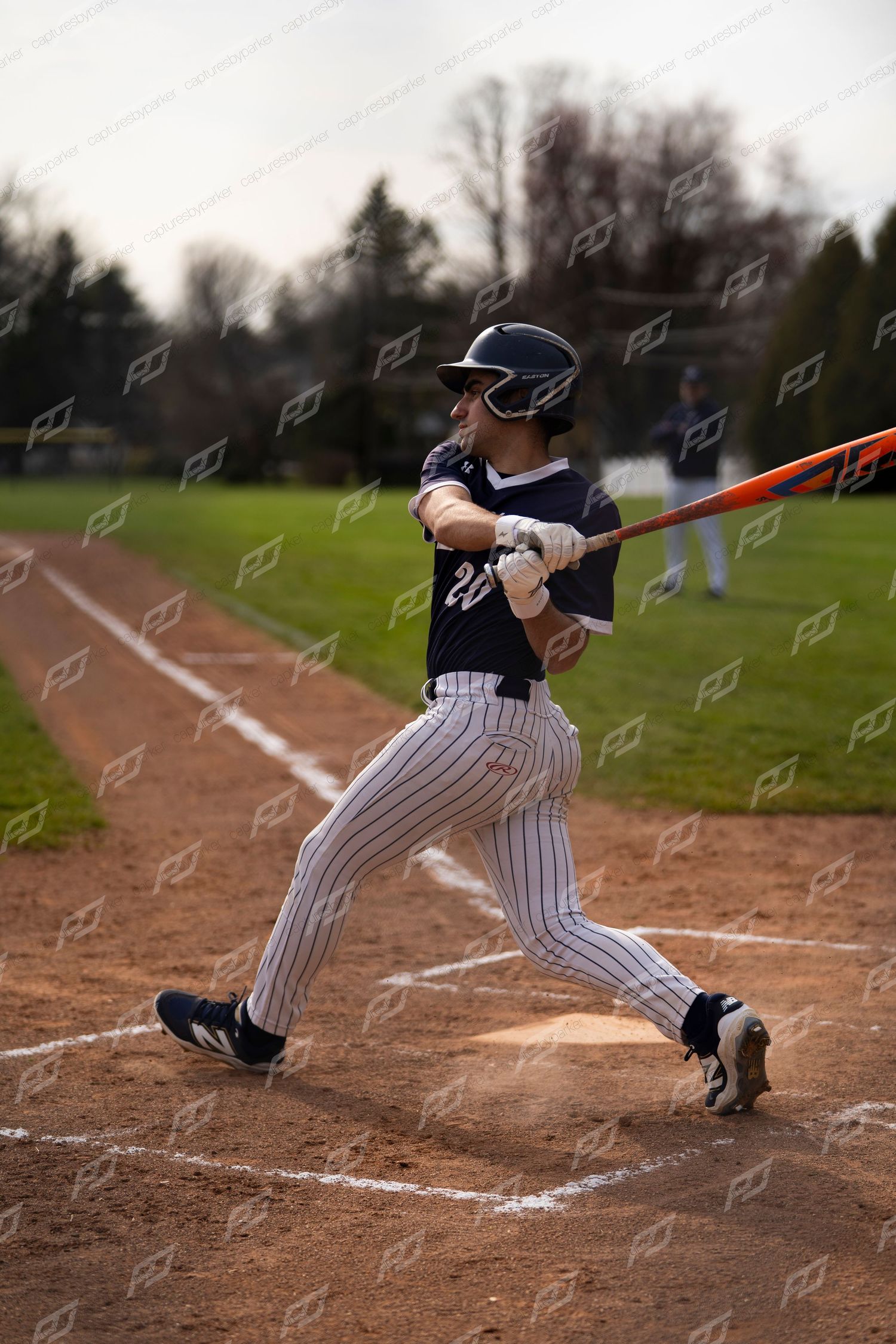 Baseball player #20 follows through on a powerful swing with an orange bat at home plate.