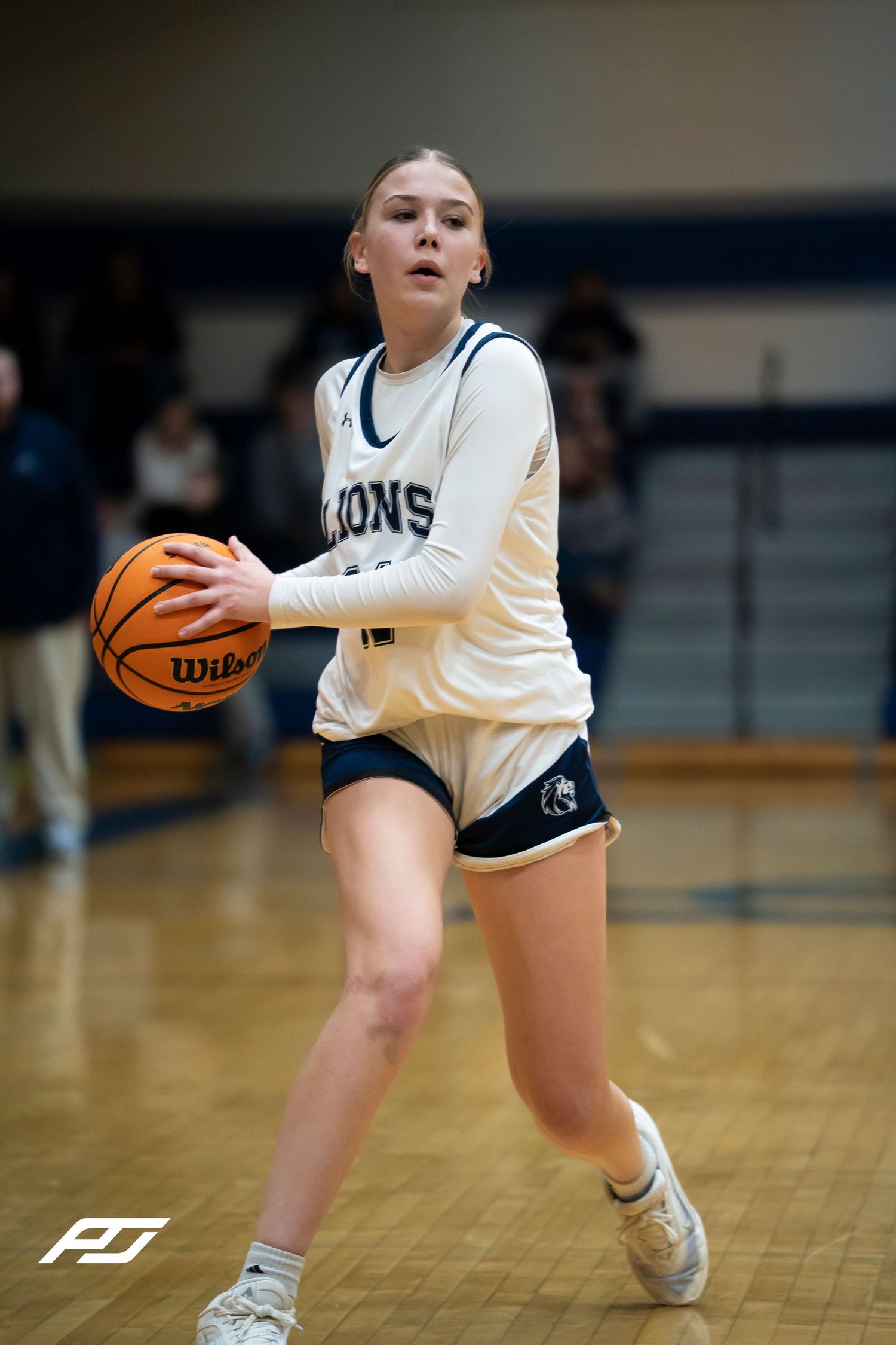 Lions girls basketball player in white jersey prepares to make a pass during a game.