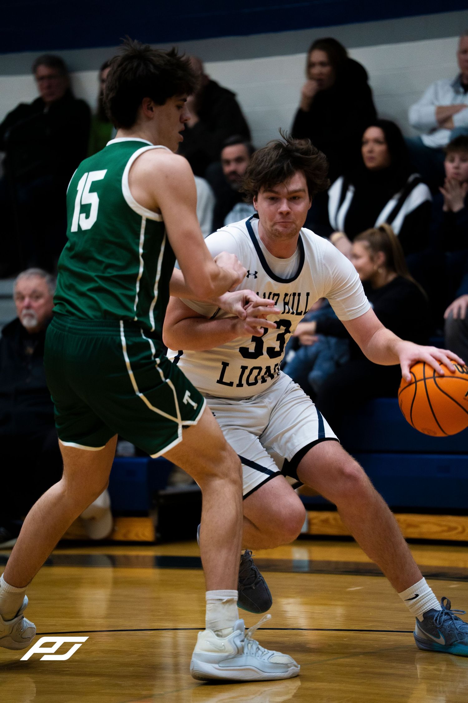 Camp Hill Lions number 33 drives past a defender wearing number 15 in green.