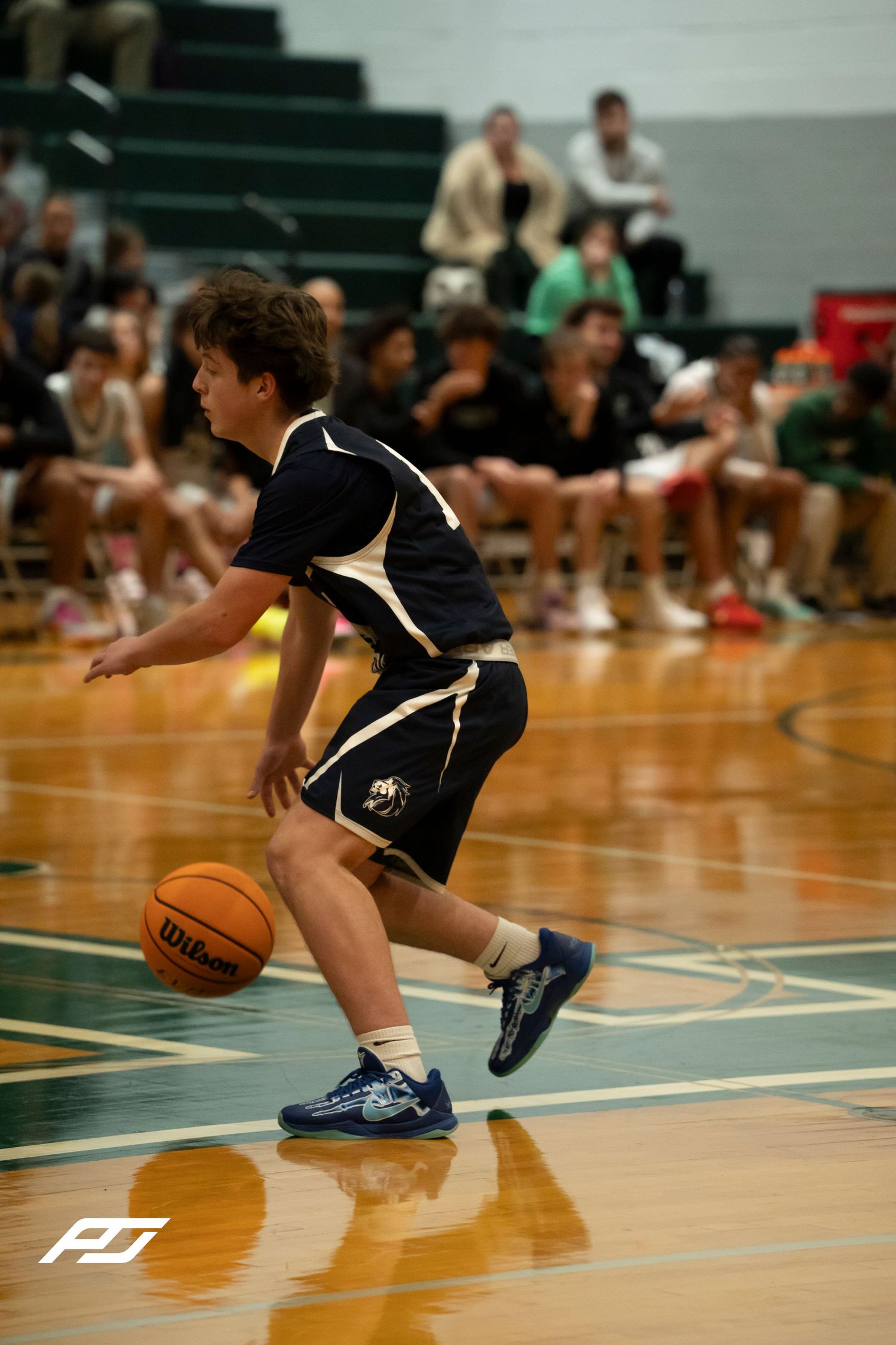 A young basketball player in navy dribbles a Wilson basketball during a game.