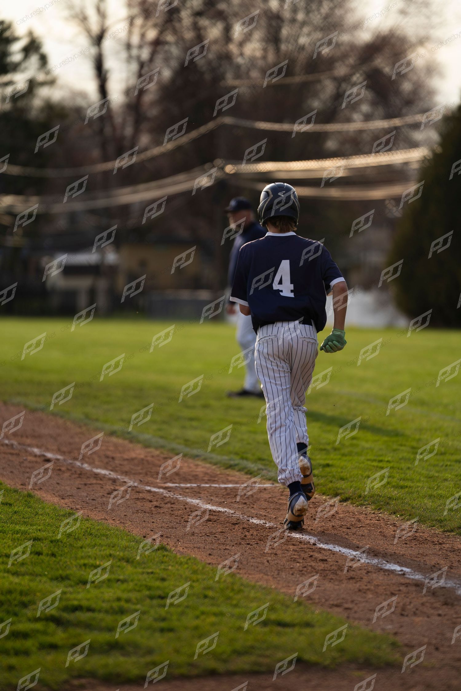 Baseball player #4 in dark pinstripe uniform jogs along the baseline with coach visible in background.