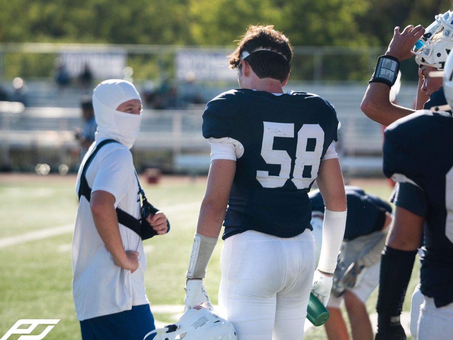 Camp Hill football player #58 walks on sideline with teammate in navy uniform during game.
