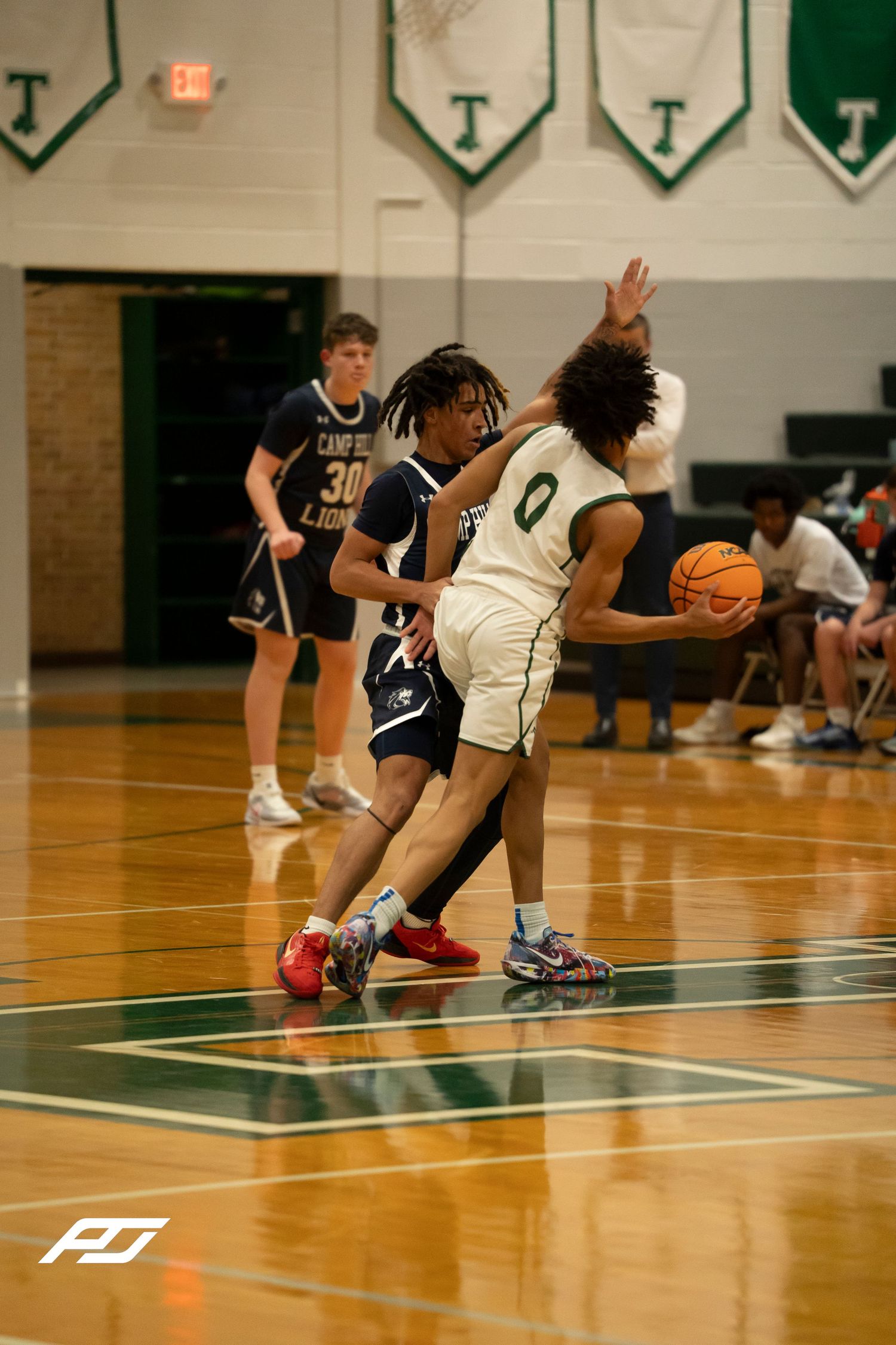 Camp Hill Lions player defends against Trinity number 0 during a high school basketball game.