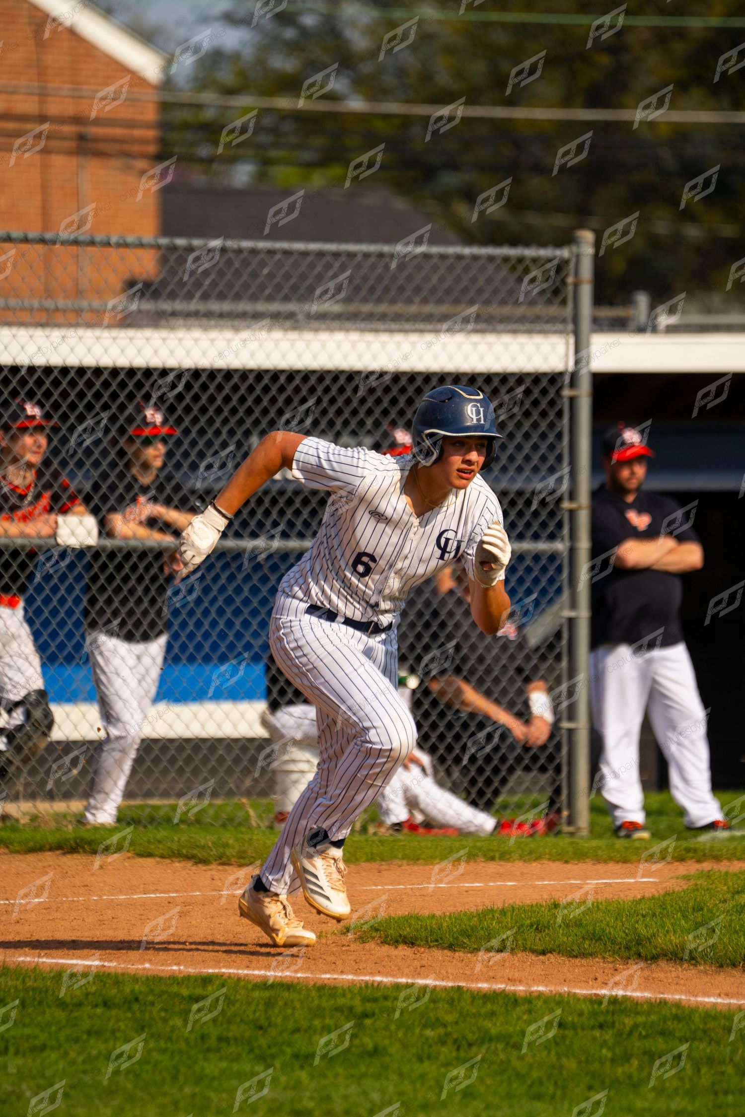 Baseball player #6 in white pinstripe uniform sprints from home plate during an outdoor game.