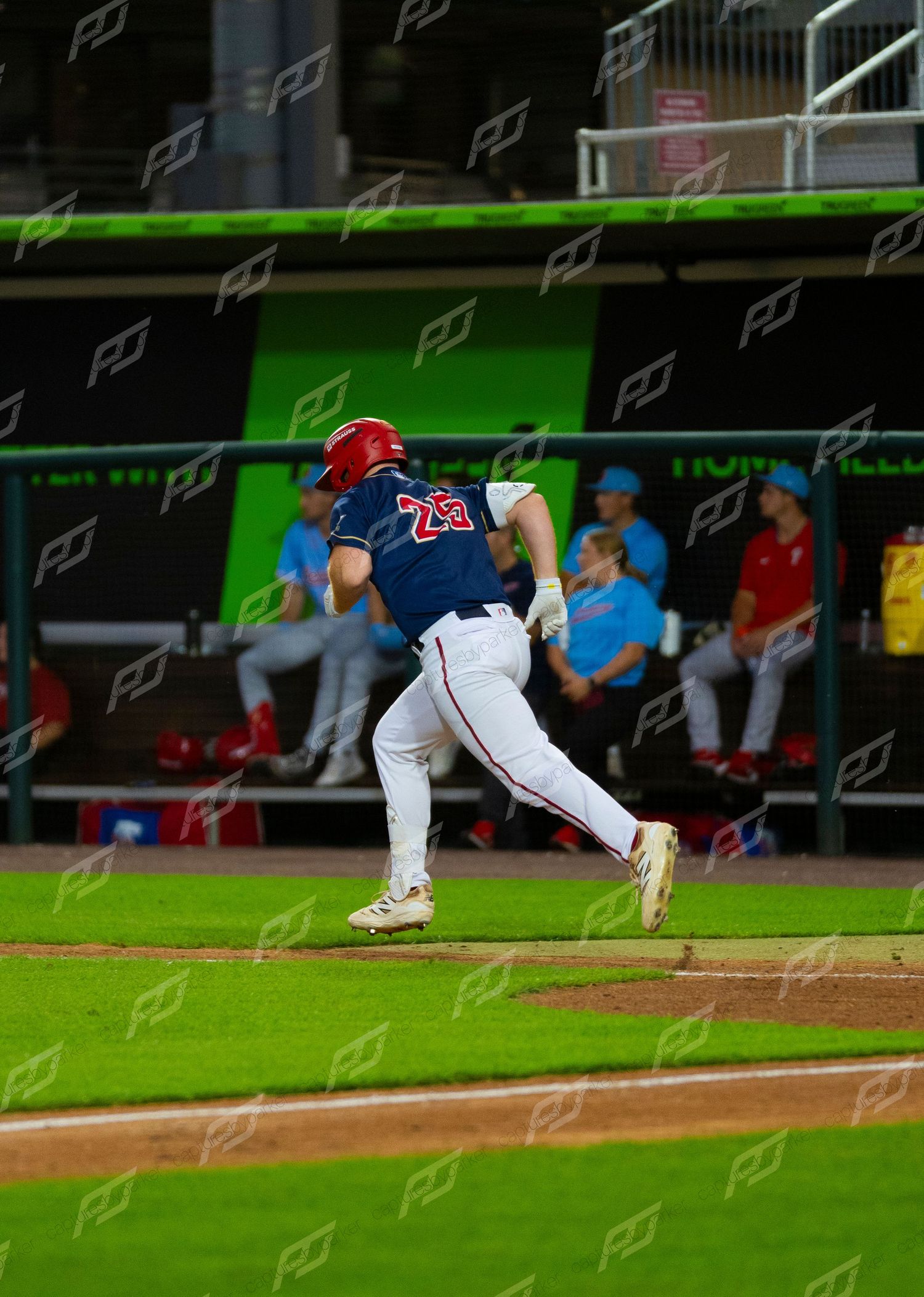 Baseball player wearing number 29 sprints down the first base line during a night game.
