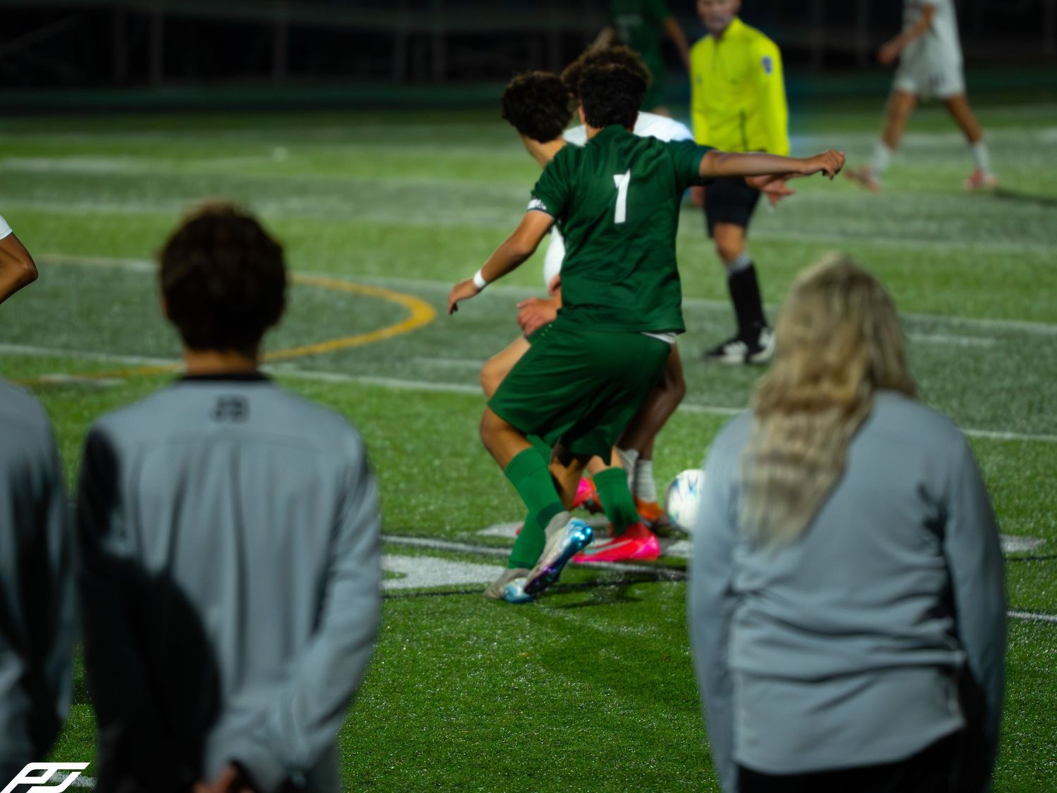Trinity soccer player #1 in green uniform competing for the ball during a night game.