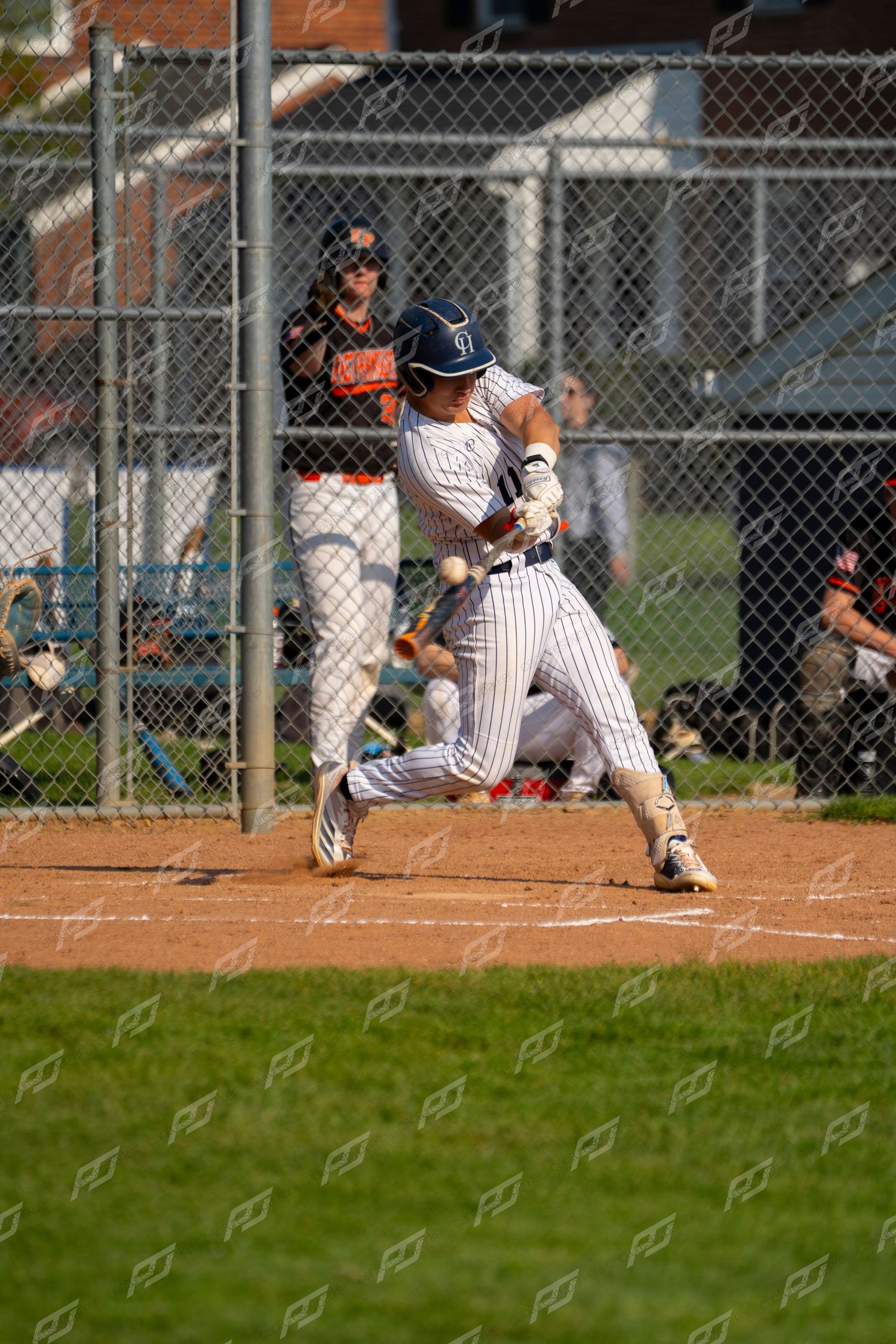 Baseball batter in pinstripe uniform makes contact during at-bat with catcher behind plate.