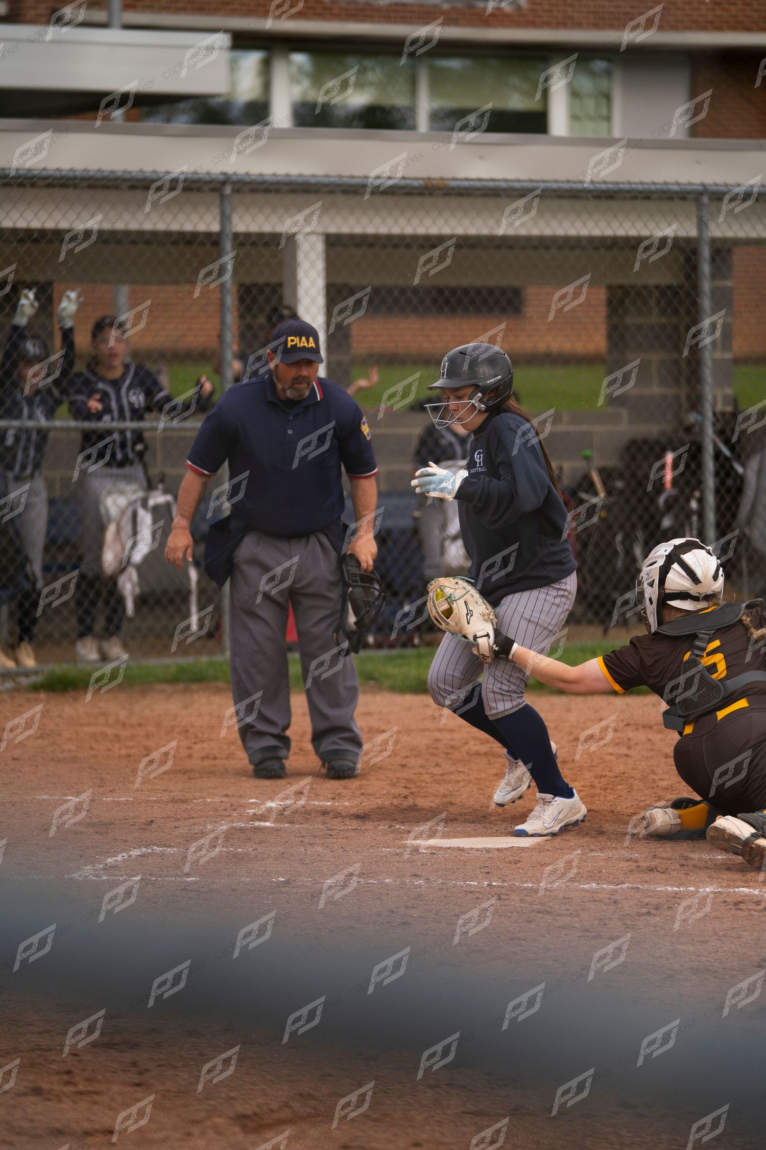 Softball batter reaches home plate as catcher and umpire watch during a game.