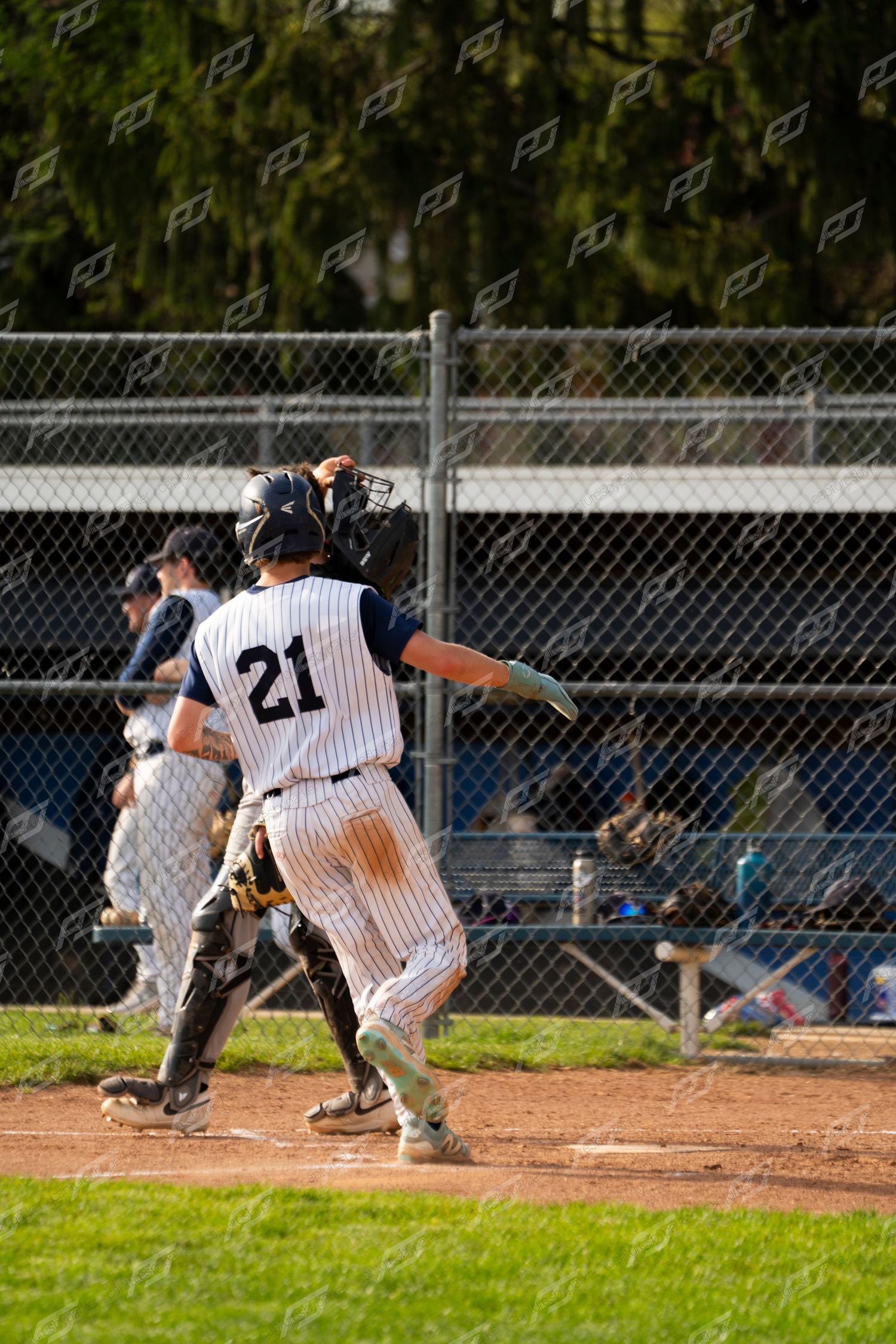 Baseball player #21 in dirty pinstripe uniform approaches home plate as catcher prepares to make a play.