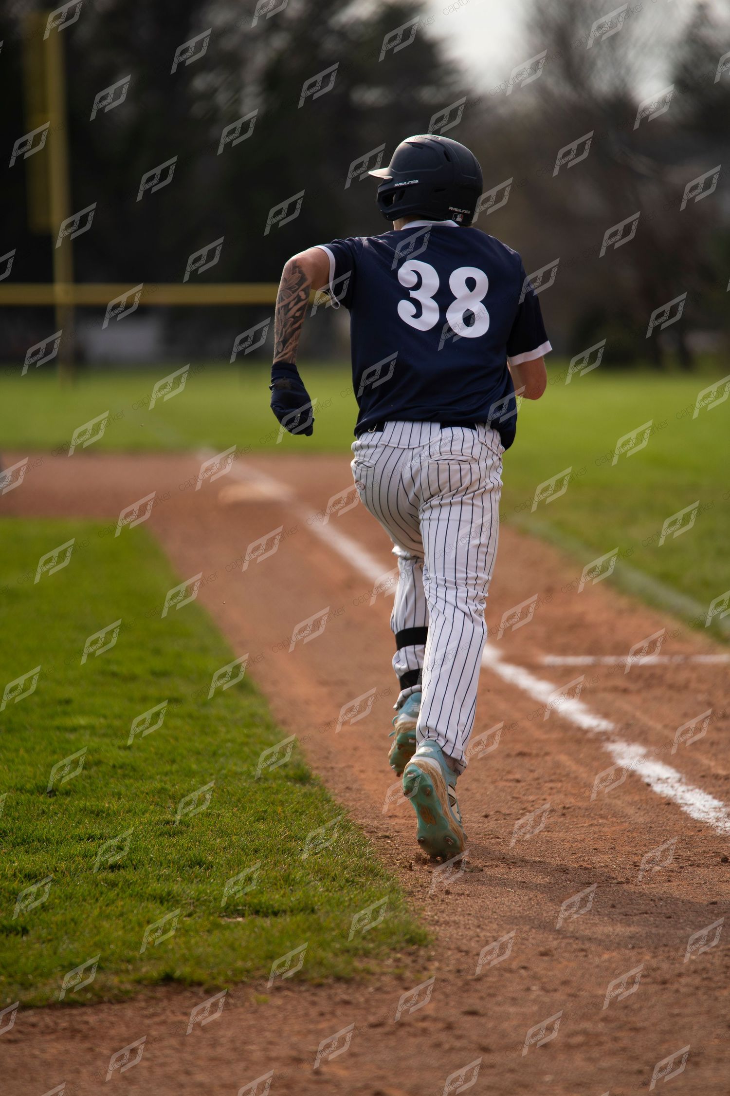 Baseball player #38 in navy pinstripe uniform runs along the baseline during game.
