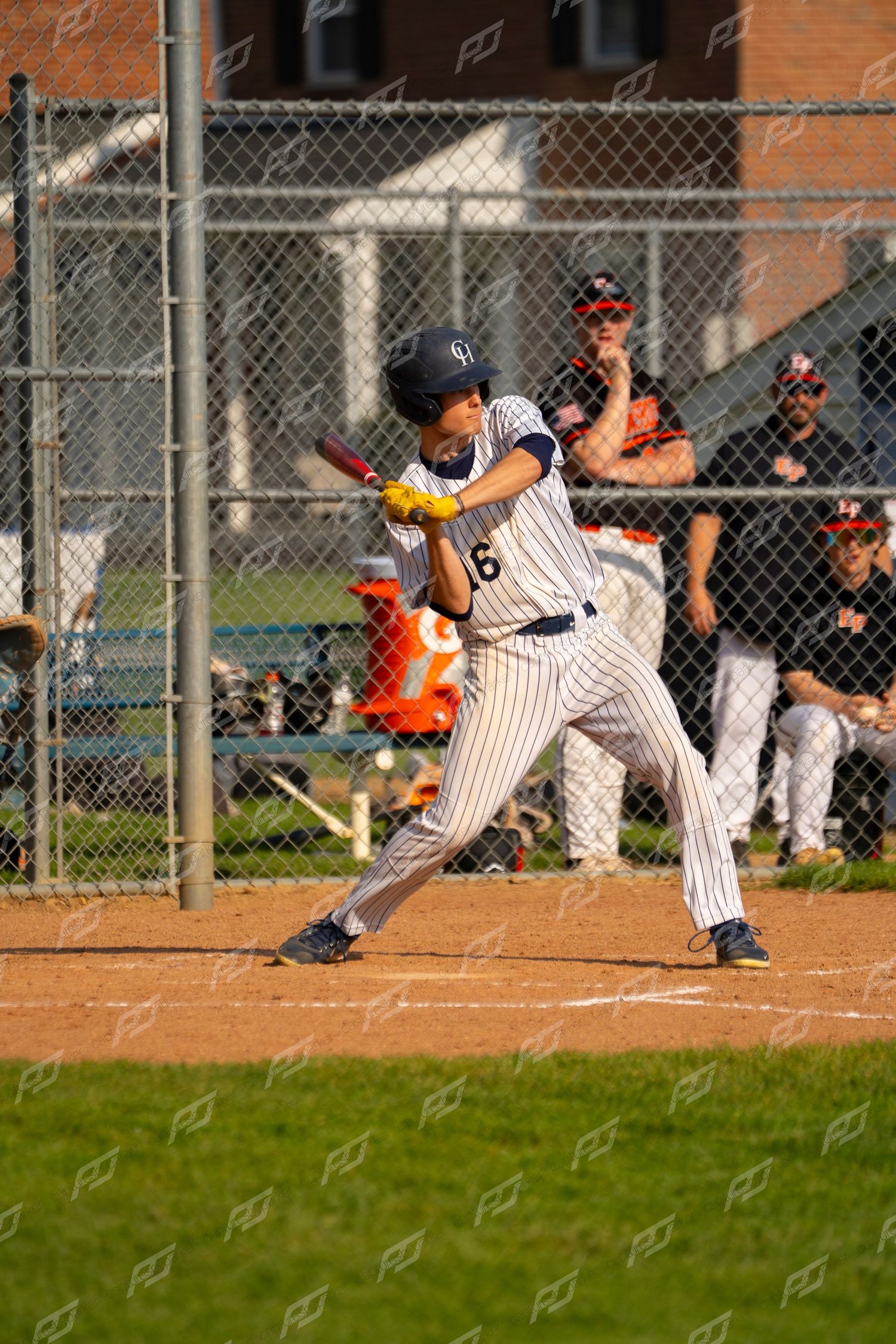 Youth baseball player #16 in white pinstripe uniform preparing to swing at home plate.