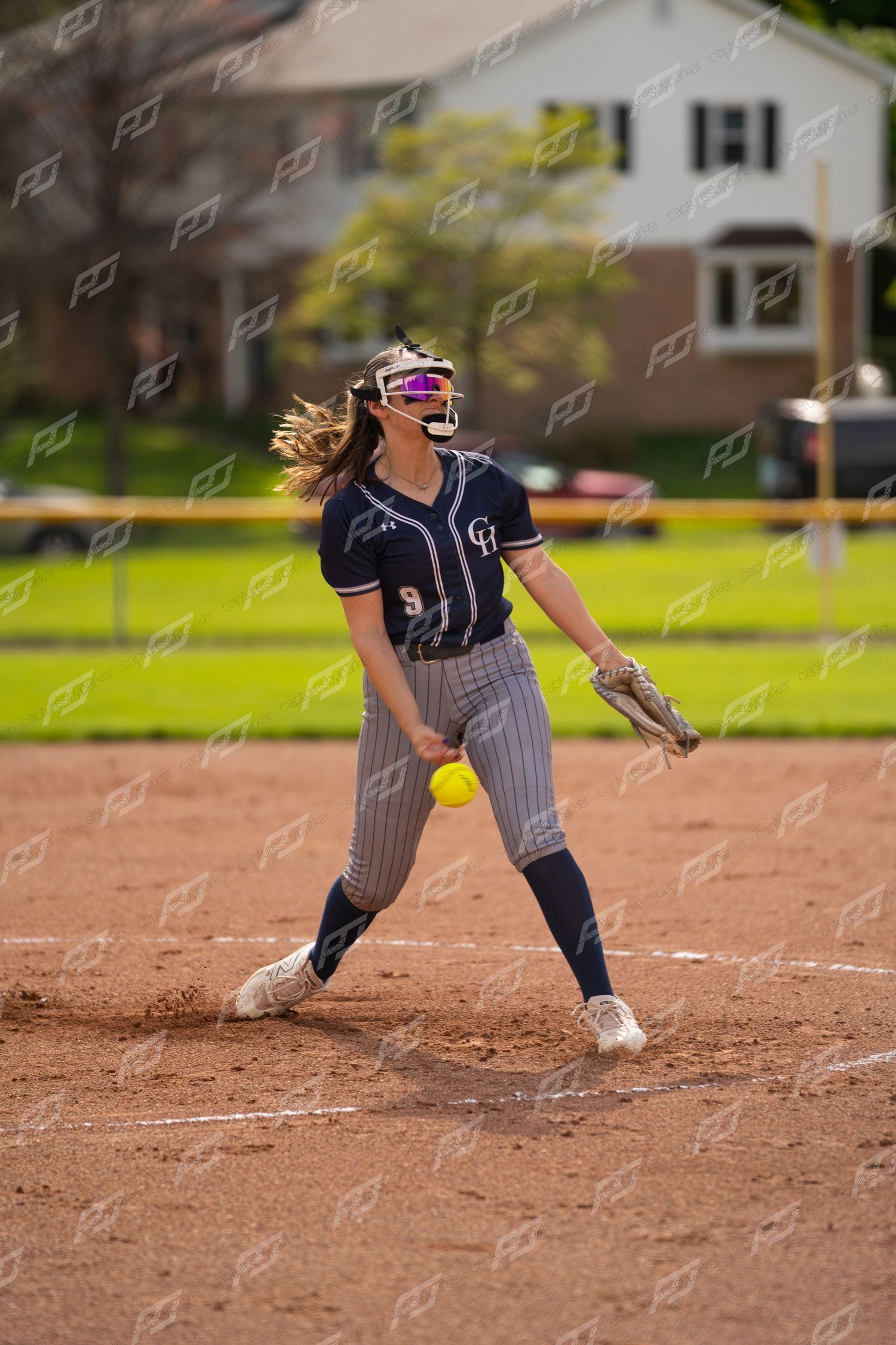 Softball pitcher #9 winds up to deliver pitch during game.