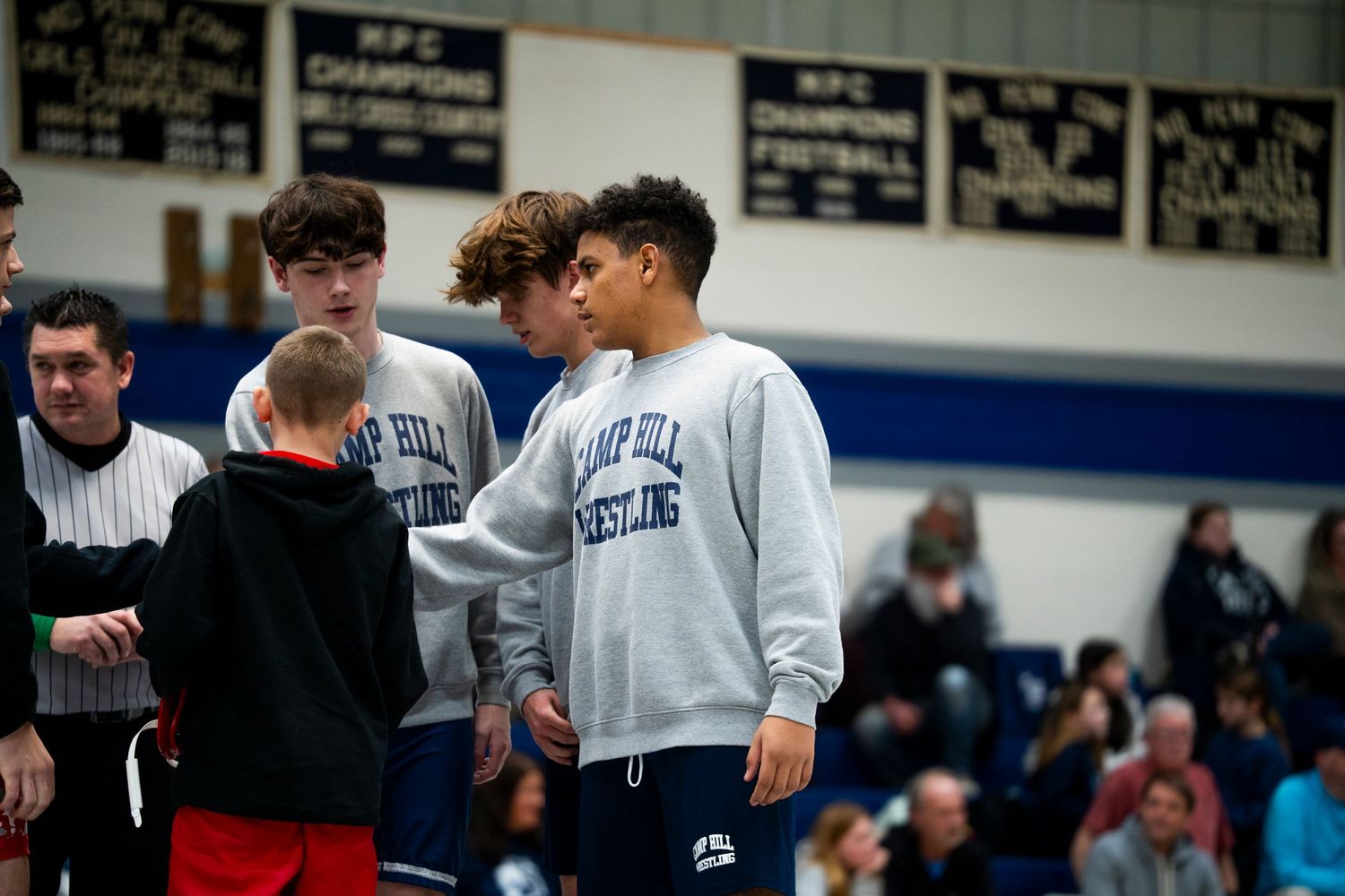 Camp Hill Wrestling team members stand together near the mat during a wrestling meet.