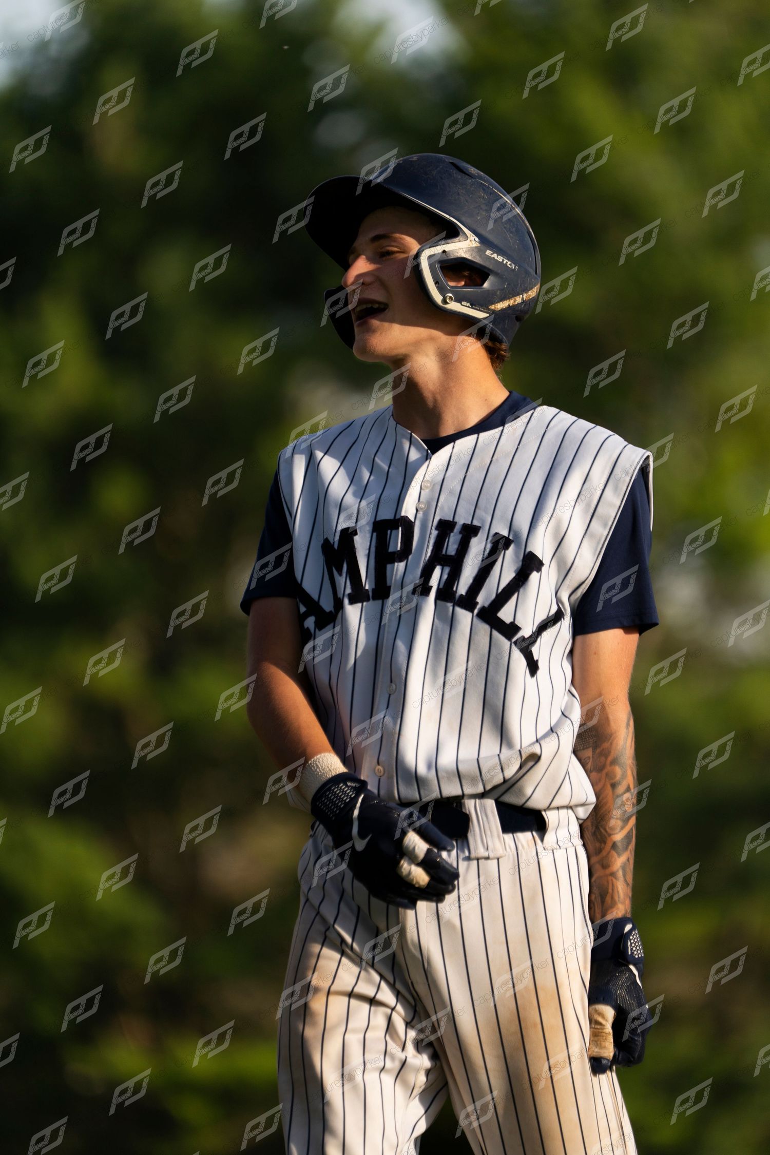 Camp Hill baseball player in pinstripe uniform reacts emotionally while standing on the field during a game.