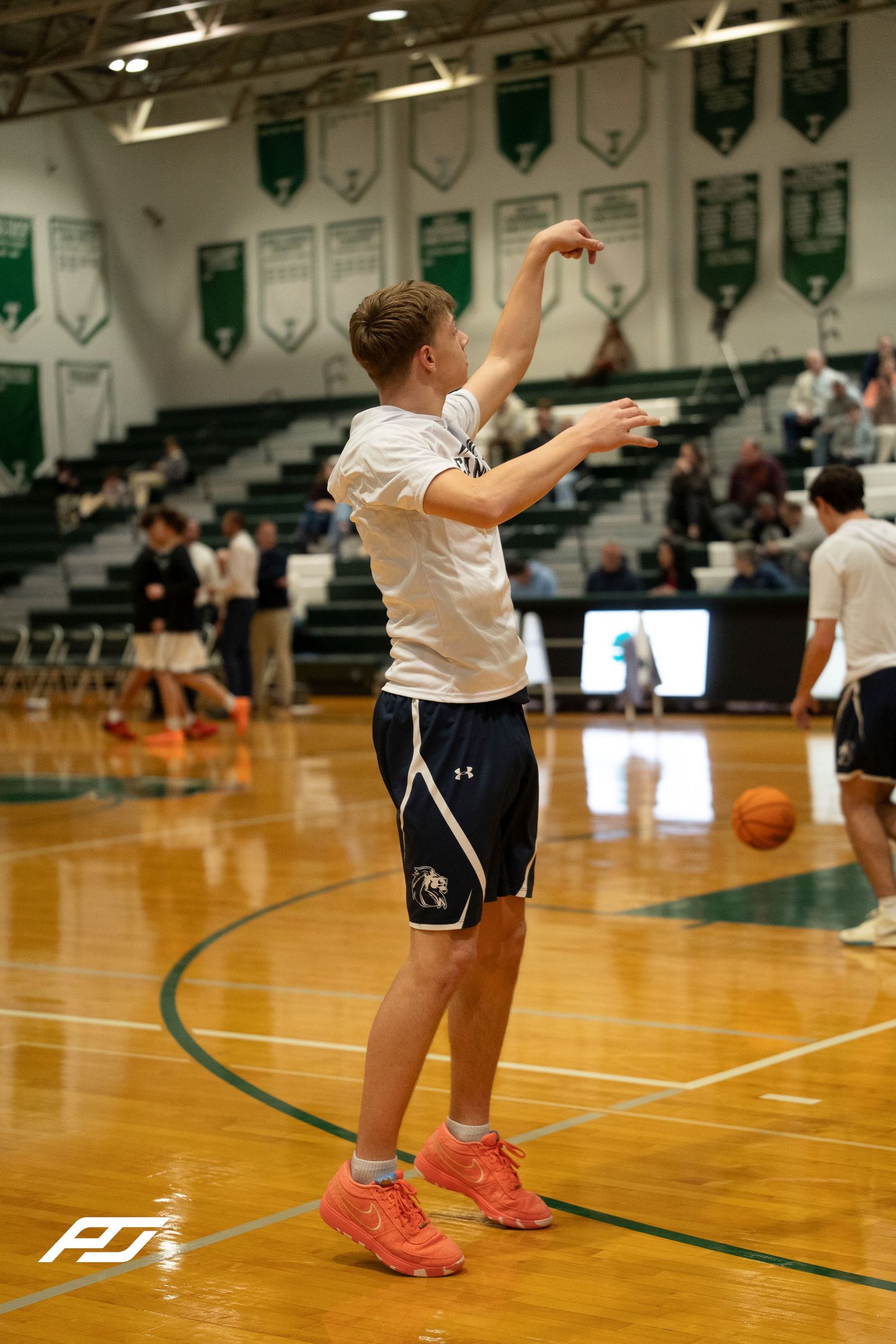 High school basketball player in white Under Armour uniform follows through on a pass during warmups.