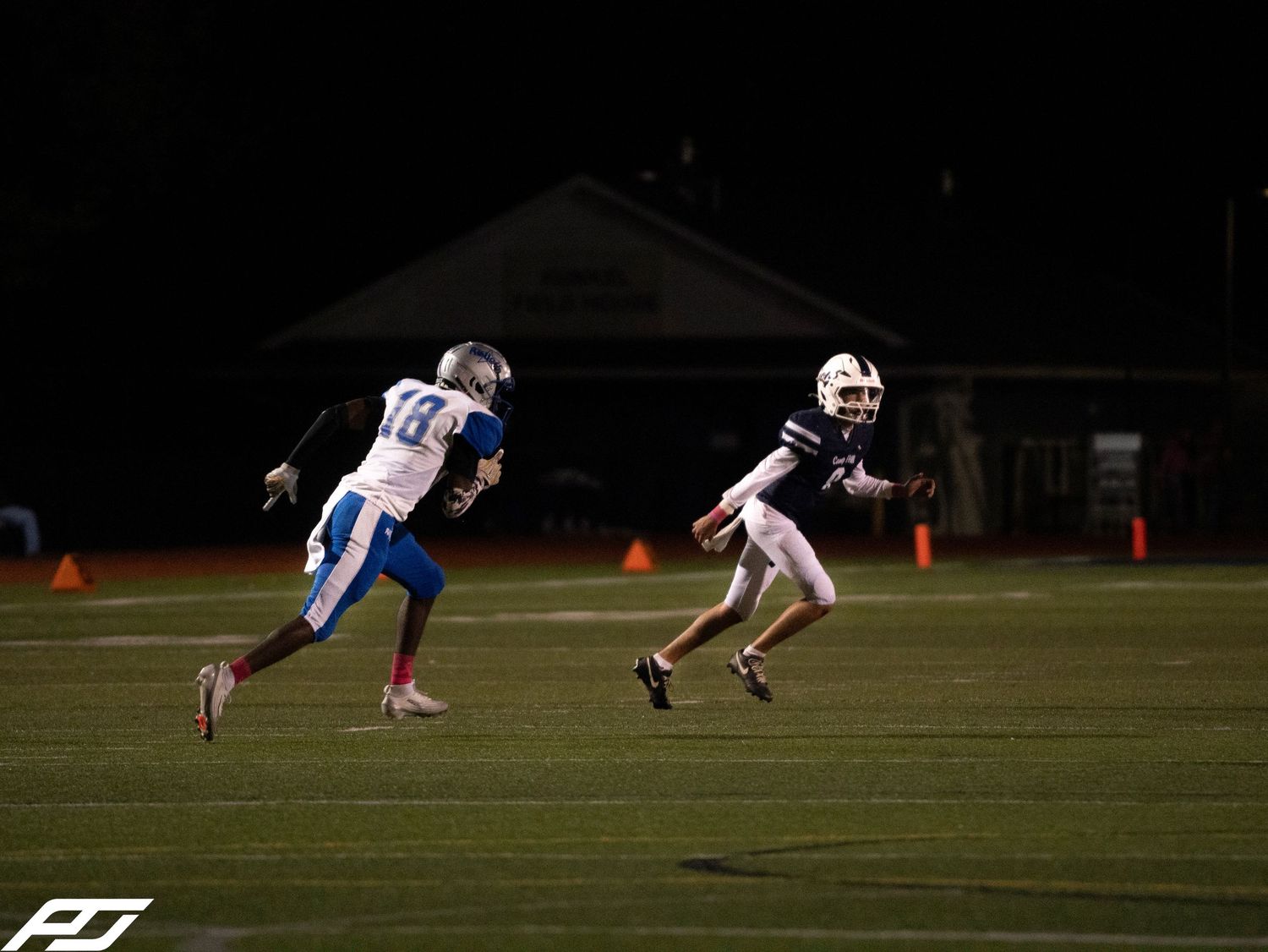 Two football players race downfield during an exciting night game play.