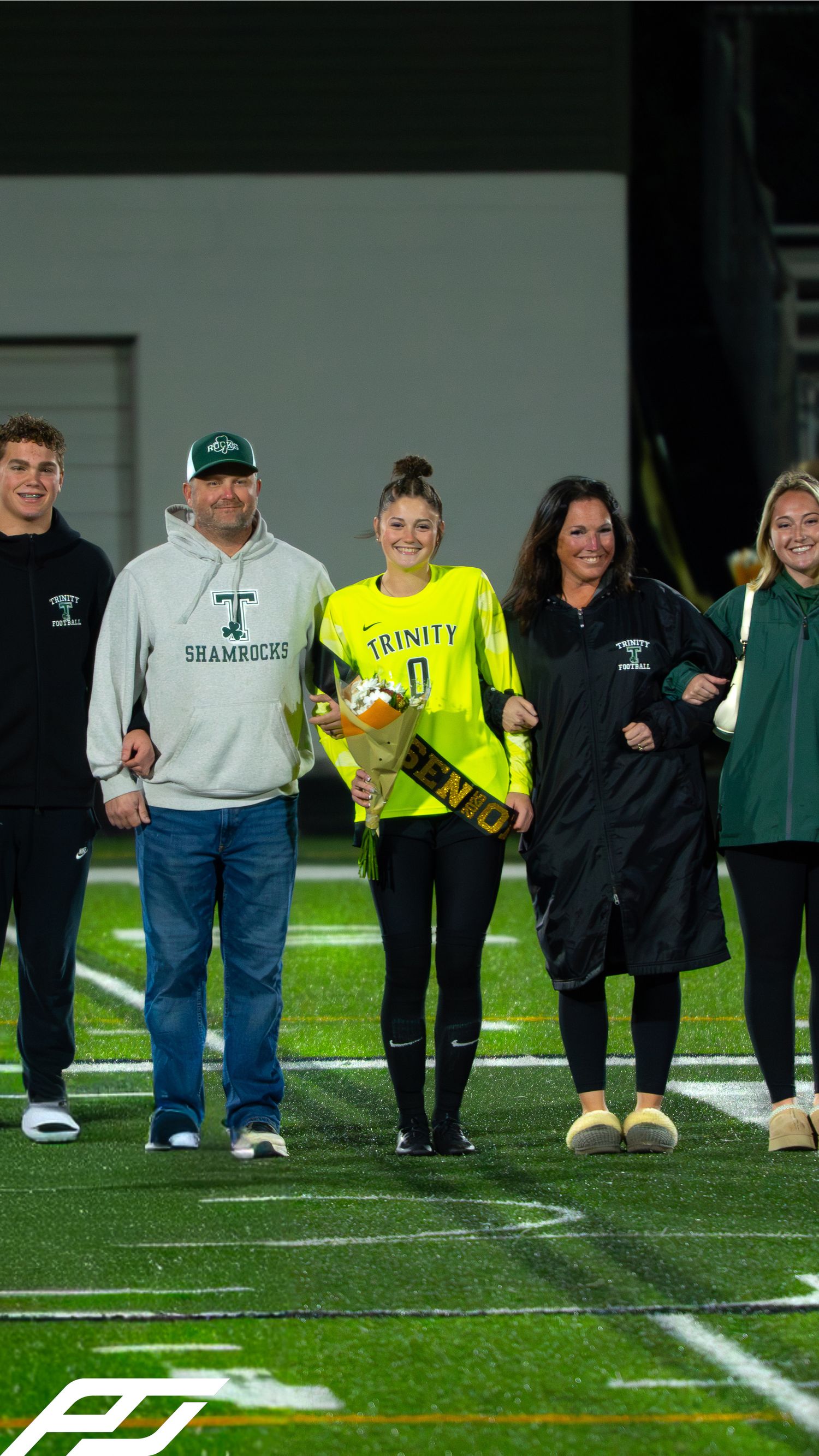 Trinity soccer player in yellow goalkeeper jersey walks with five family members during senior night ceremony.