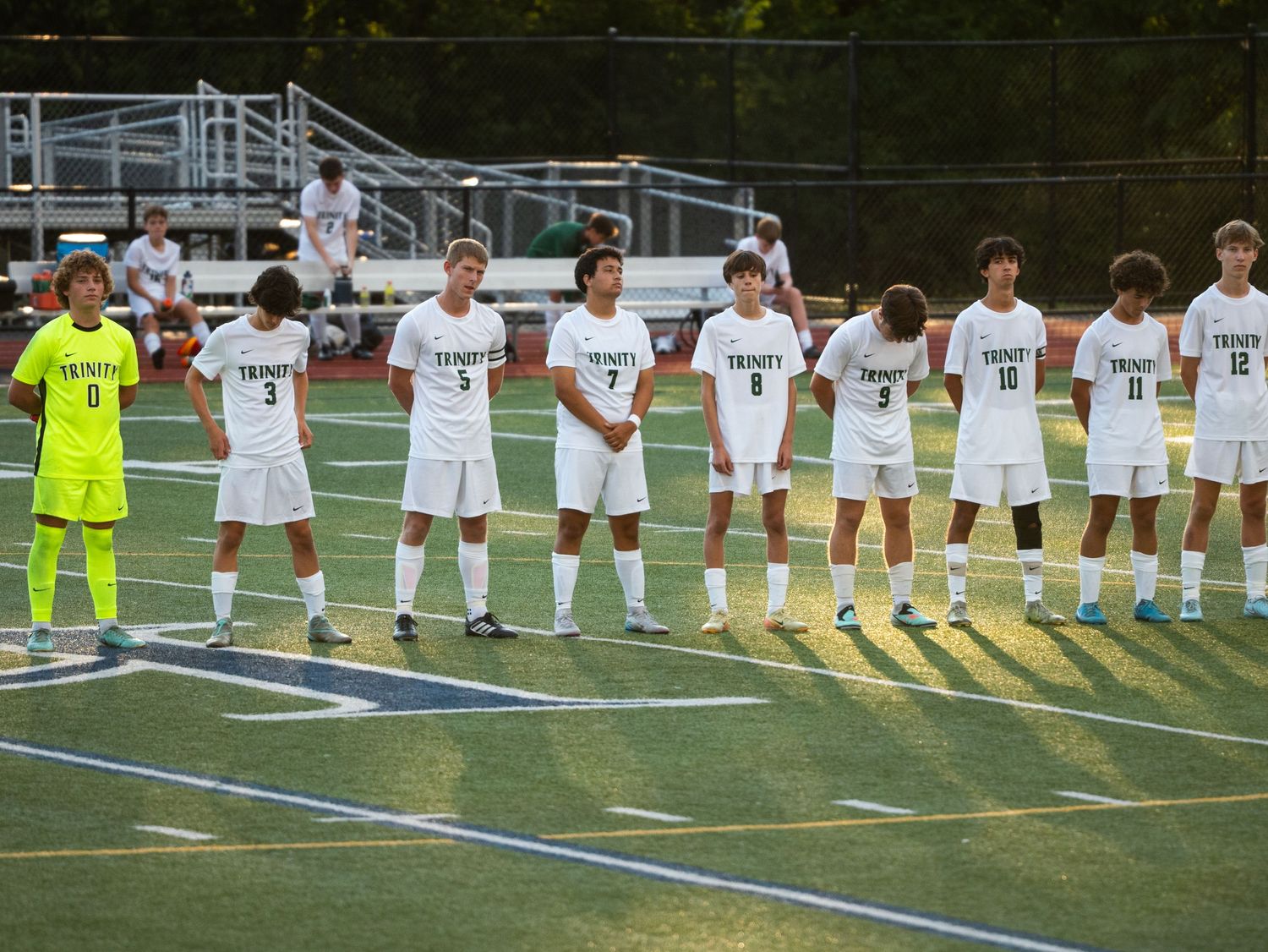 Trinity soccer team lines up in white uniforms on the field before a match.