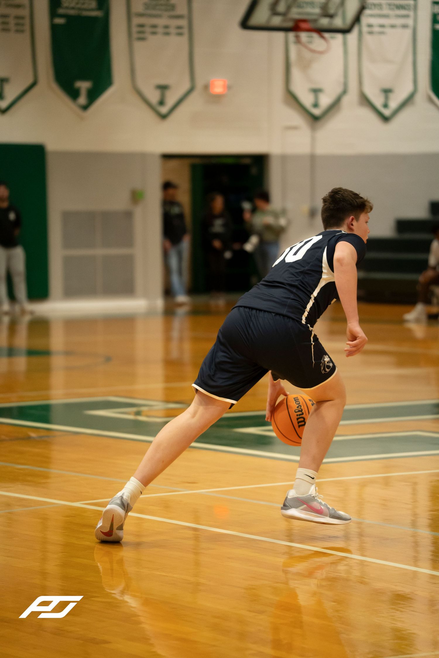 Number 10 basketball player in navy uniform dribbles ball during a high school basketball game.