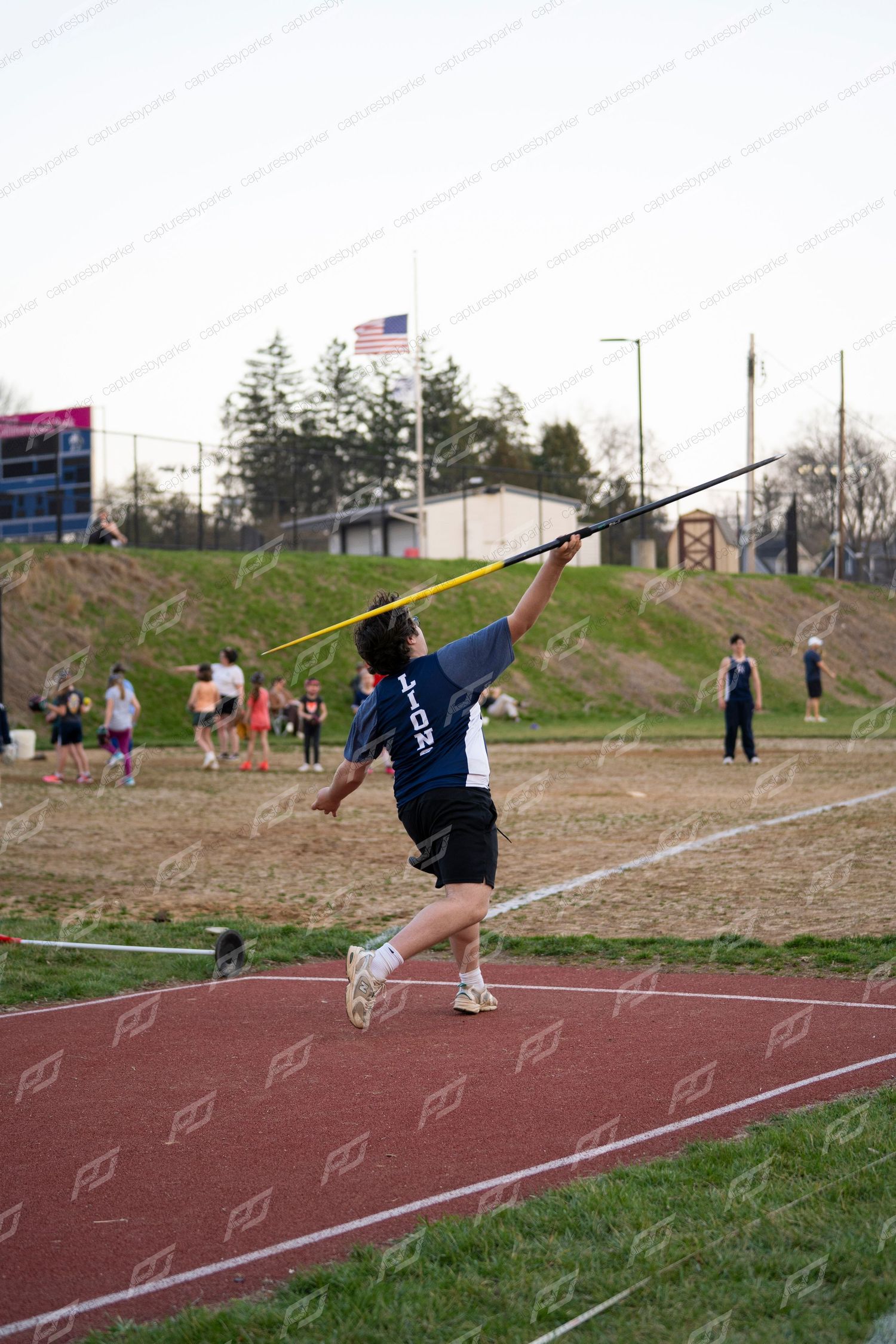 Male Lions athlete throwing javelin at outdoor high school track meet.