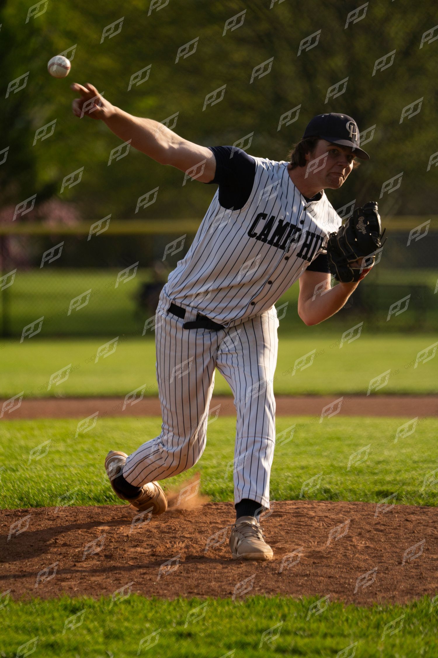 Camp Hill baseball pitcher in pinstripe uniform delivers a pitch during a sunny youth baseball game.