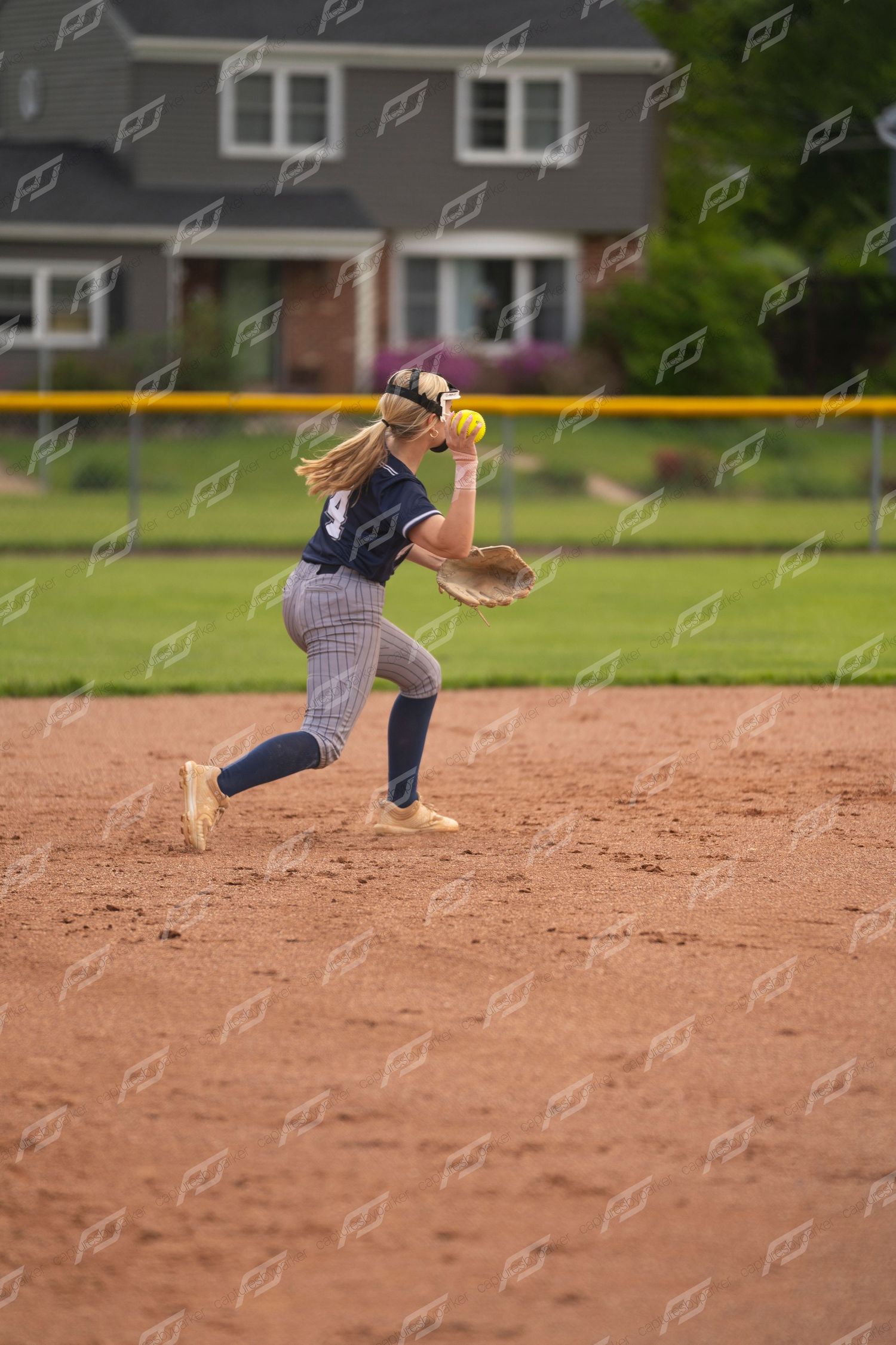 Female softball player winds up to throw the ball during an infield play.