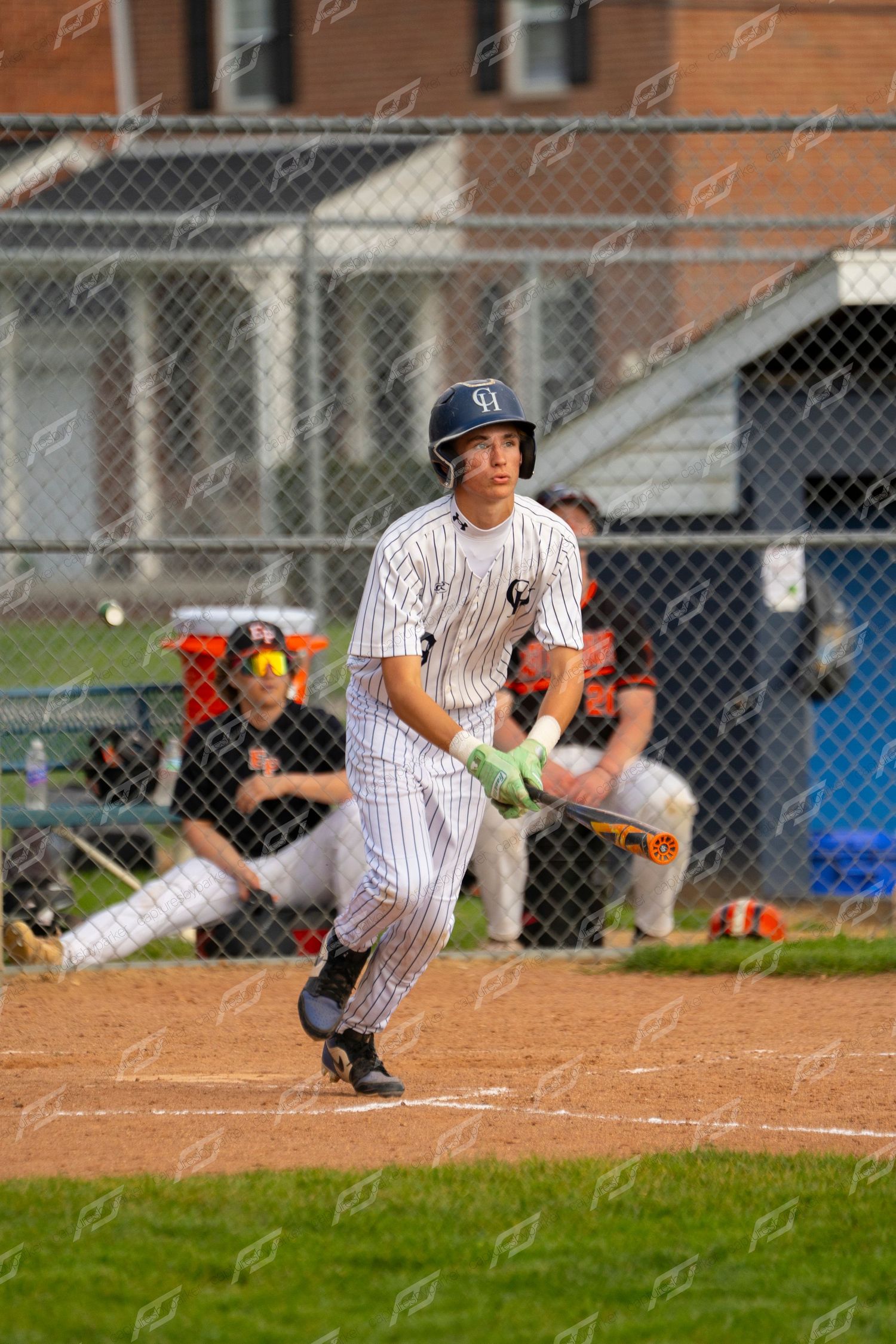 Baseball batter in pinstripe uniform watching the ball after making contact at home plate.