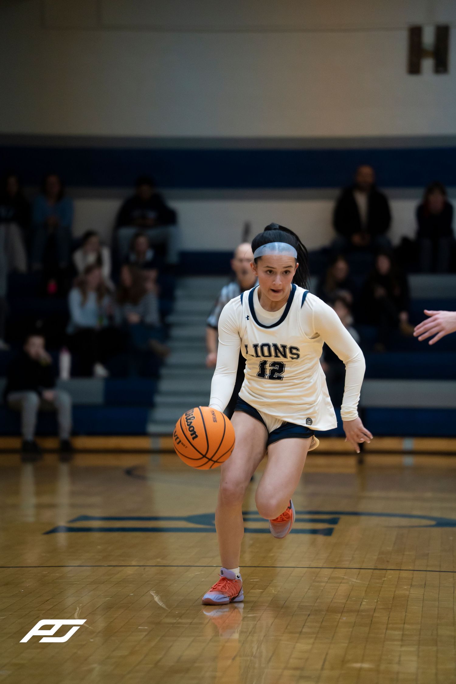 Lions number 12 dribbles the ball upcourt during a girls high school basketball game.